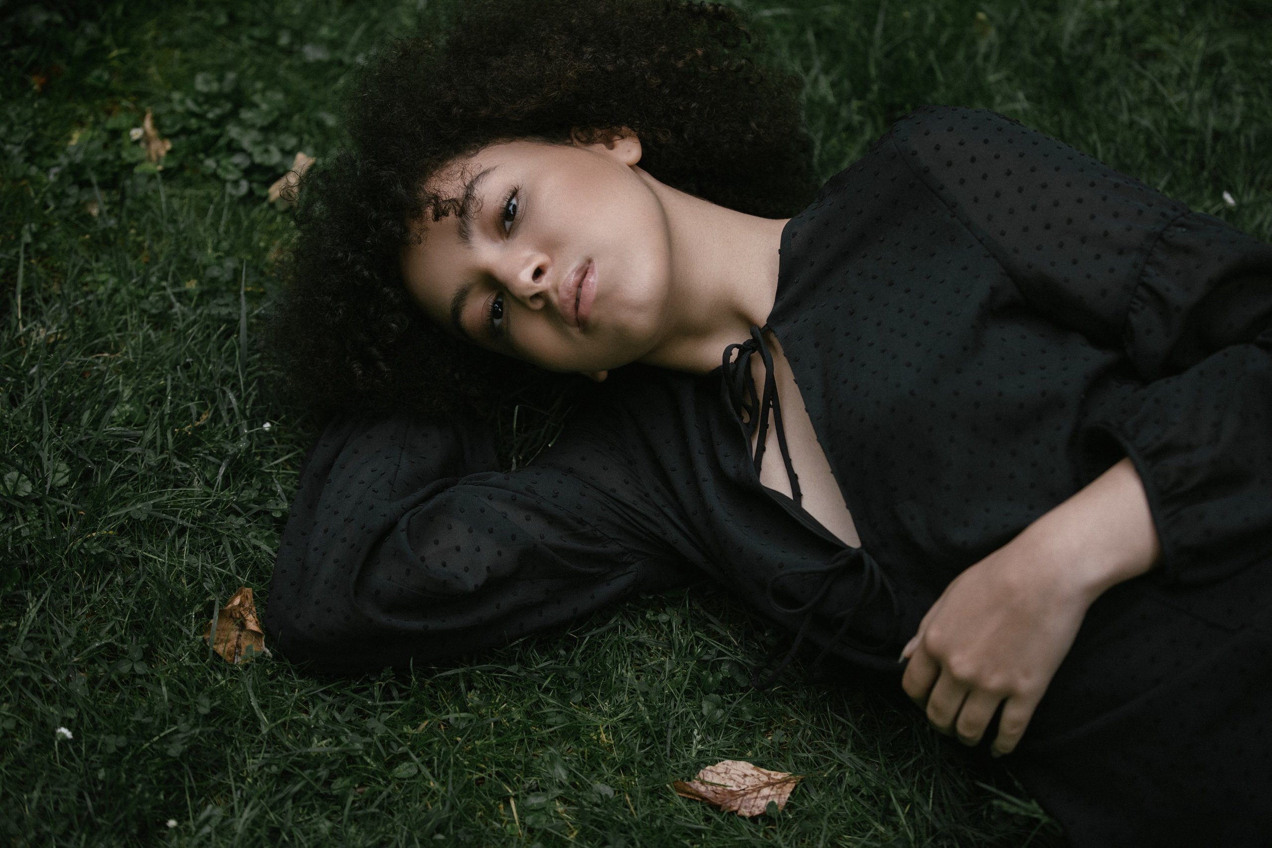 Outdoor portrait, woman lying in grass, hand under head