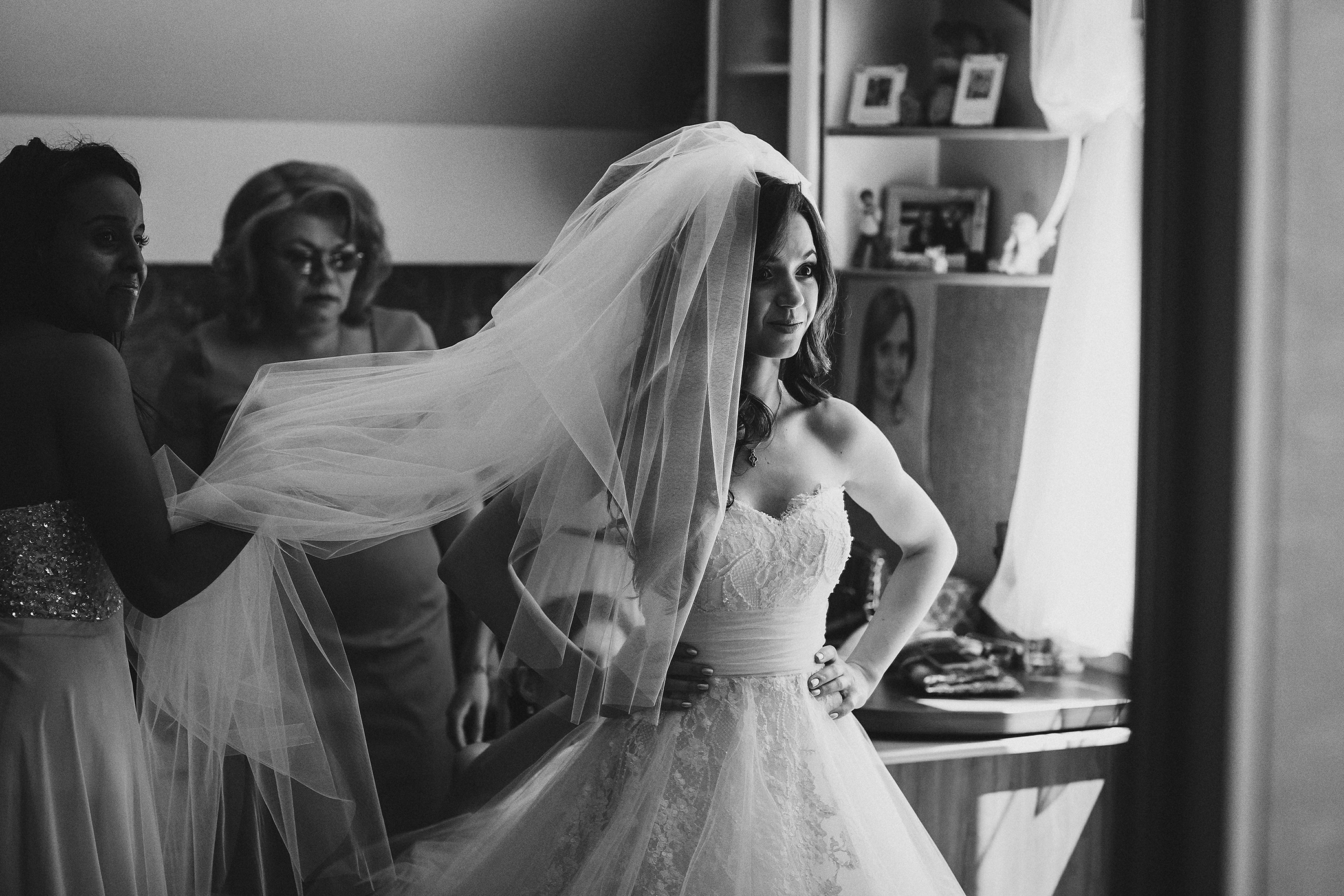 Фотограф в Ирландии чёрно-белая невеста одевает платье свадебное поправляет подружки мама