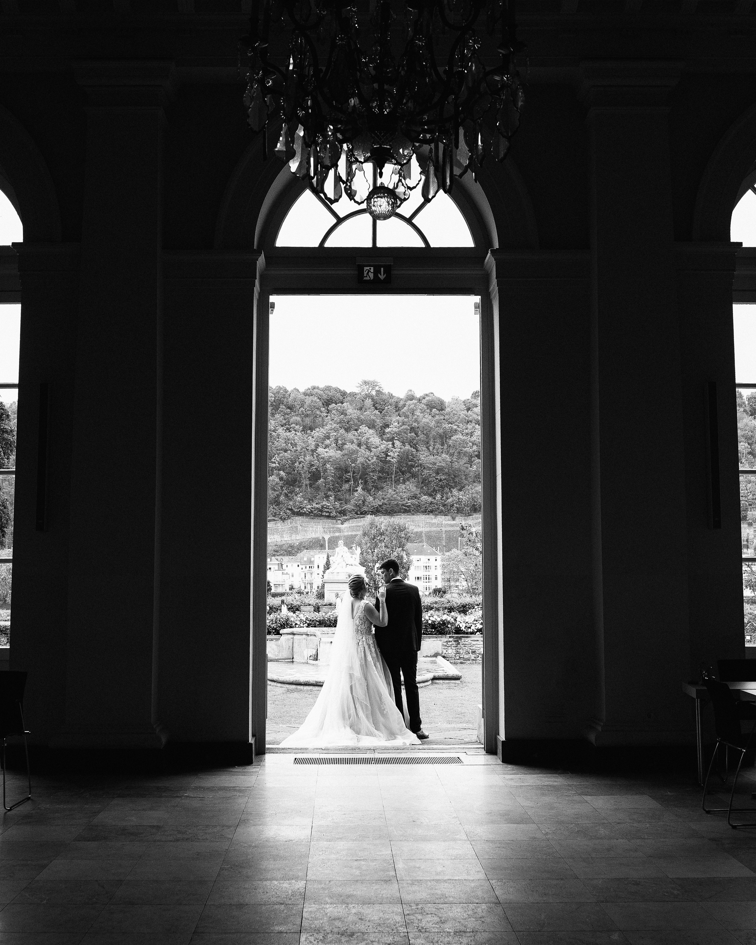 Verliebtes Brautpaar posiert vor einem imposanten Schloss, das die Kulisse des großen Tages bildet