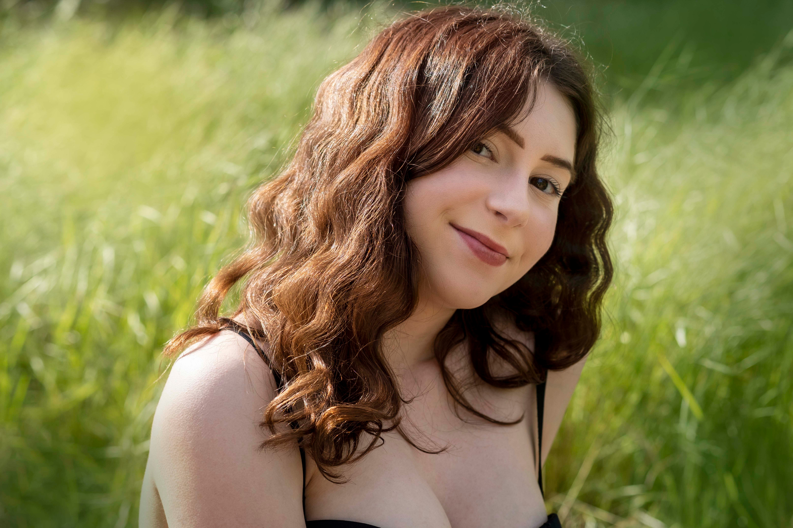 portrait of the young girl with red hair and green grass background