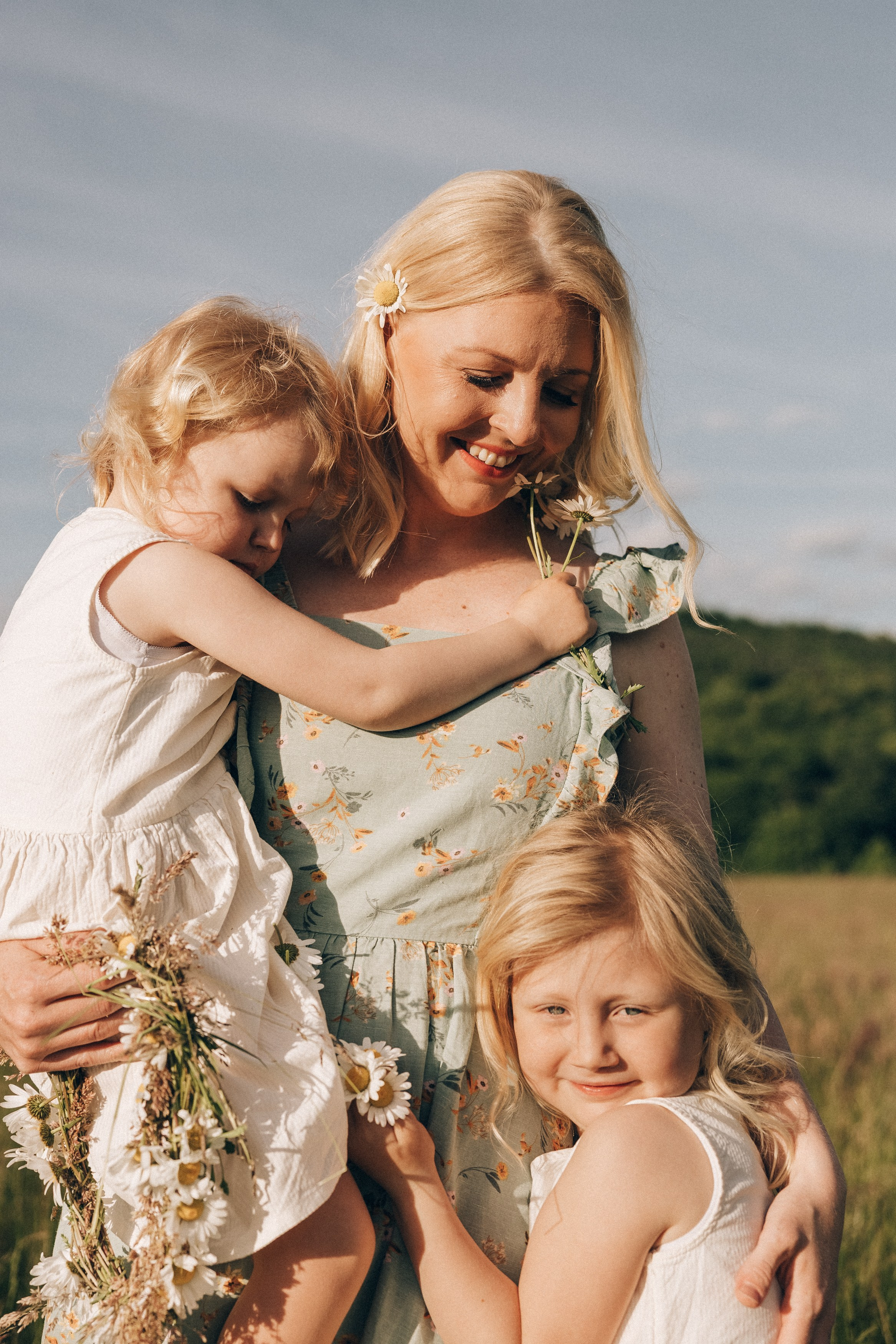 Family photoshoot in a daisy meadow at golden hour — natural light, warm tones, candid moments between a mother and her daughters. Lifestyle and Family Photographer in Pisek Oxana Telupilova