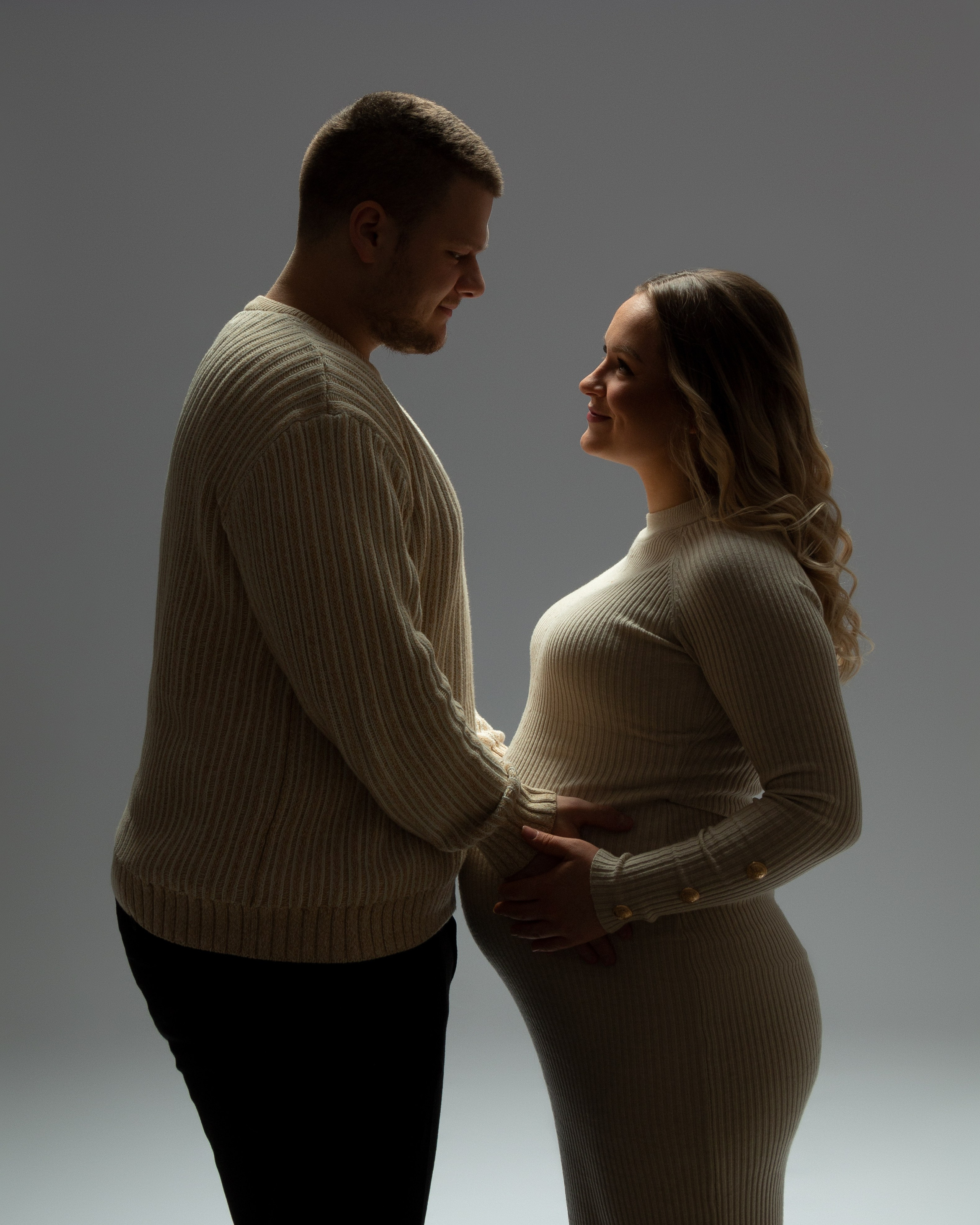 Werdende Mutter Nicole und ihr Partner stehten stolz mit offenem Blick – minimalistisches Schwangerschaftsporträt