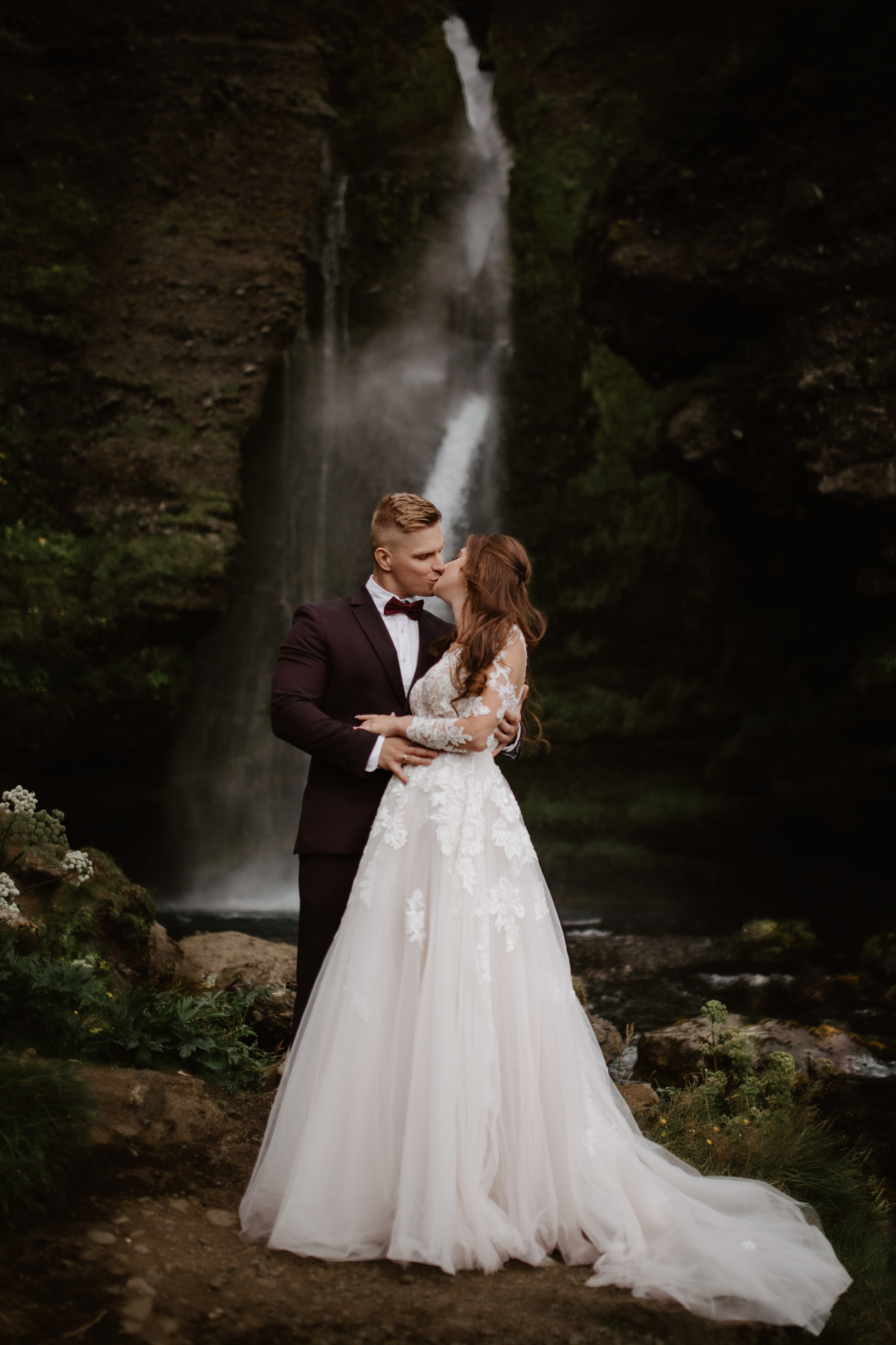 Love in the wild—couple sharing a quiet moment in front of a majestic Icelandic waterfall.