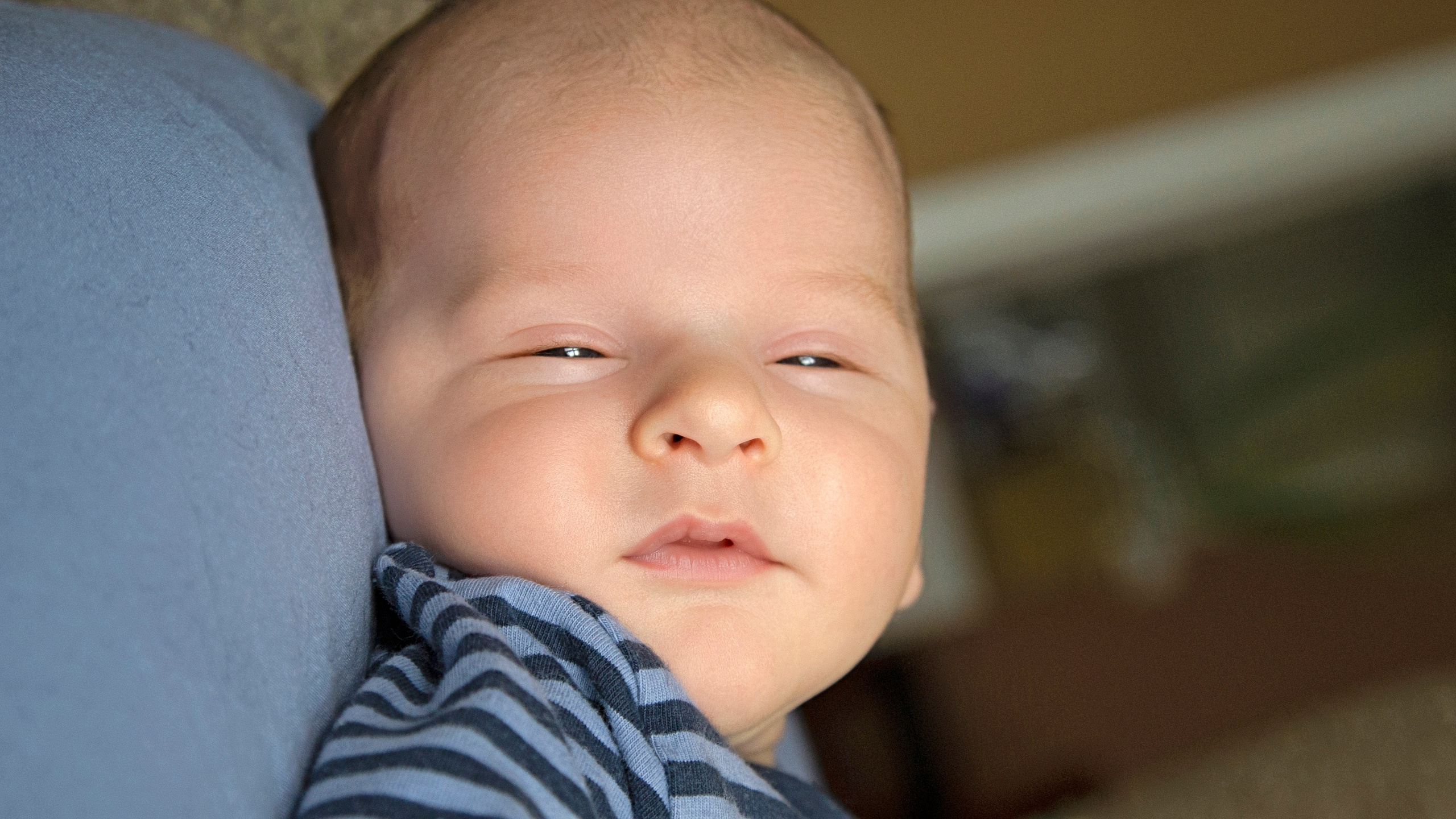 Newborn baby lying peacefully with closed eyes, wrapped in a soft blanket.