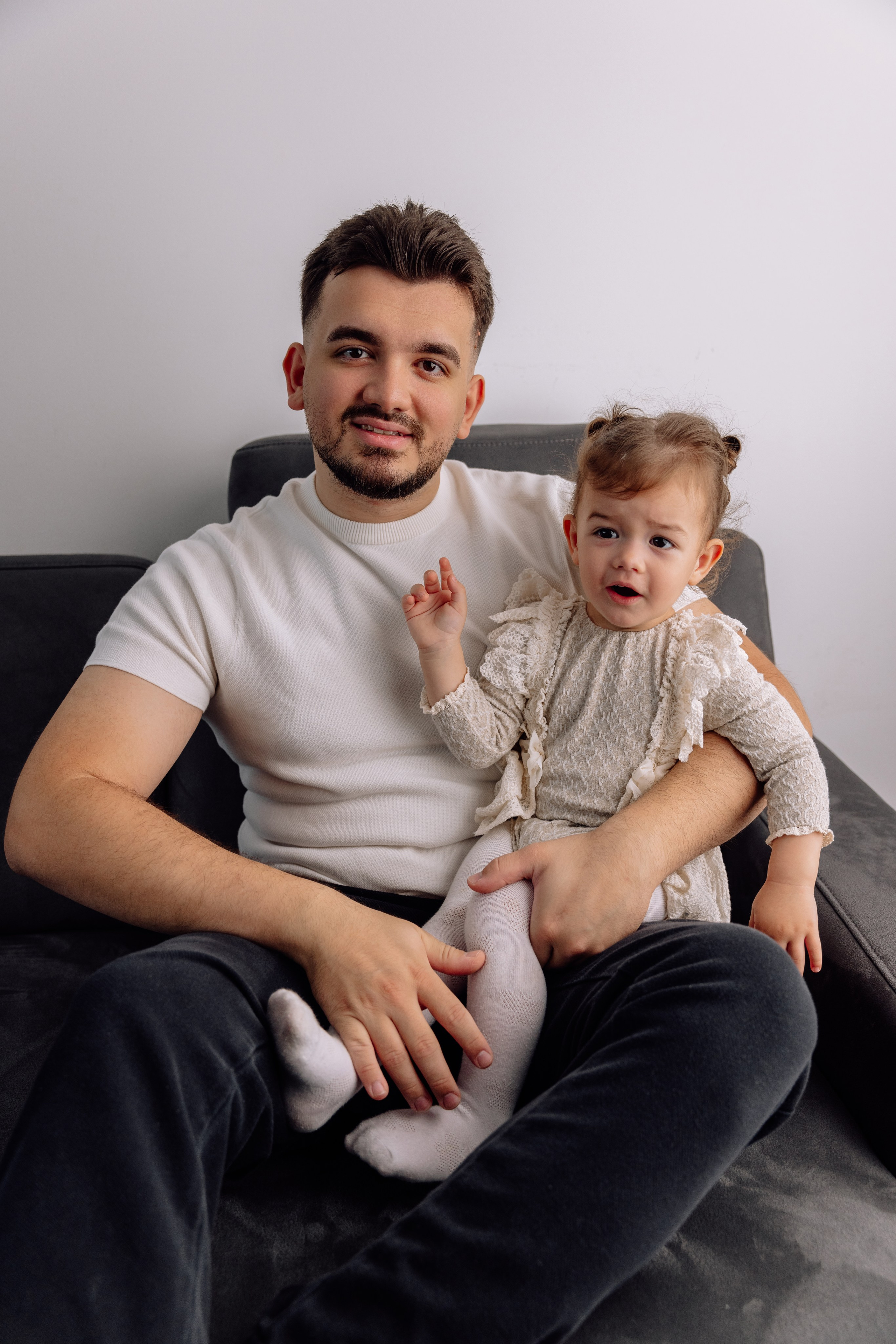 Eltern umarmen das Baby – liebevolle Szene auf dem Sofa in München.