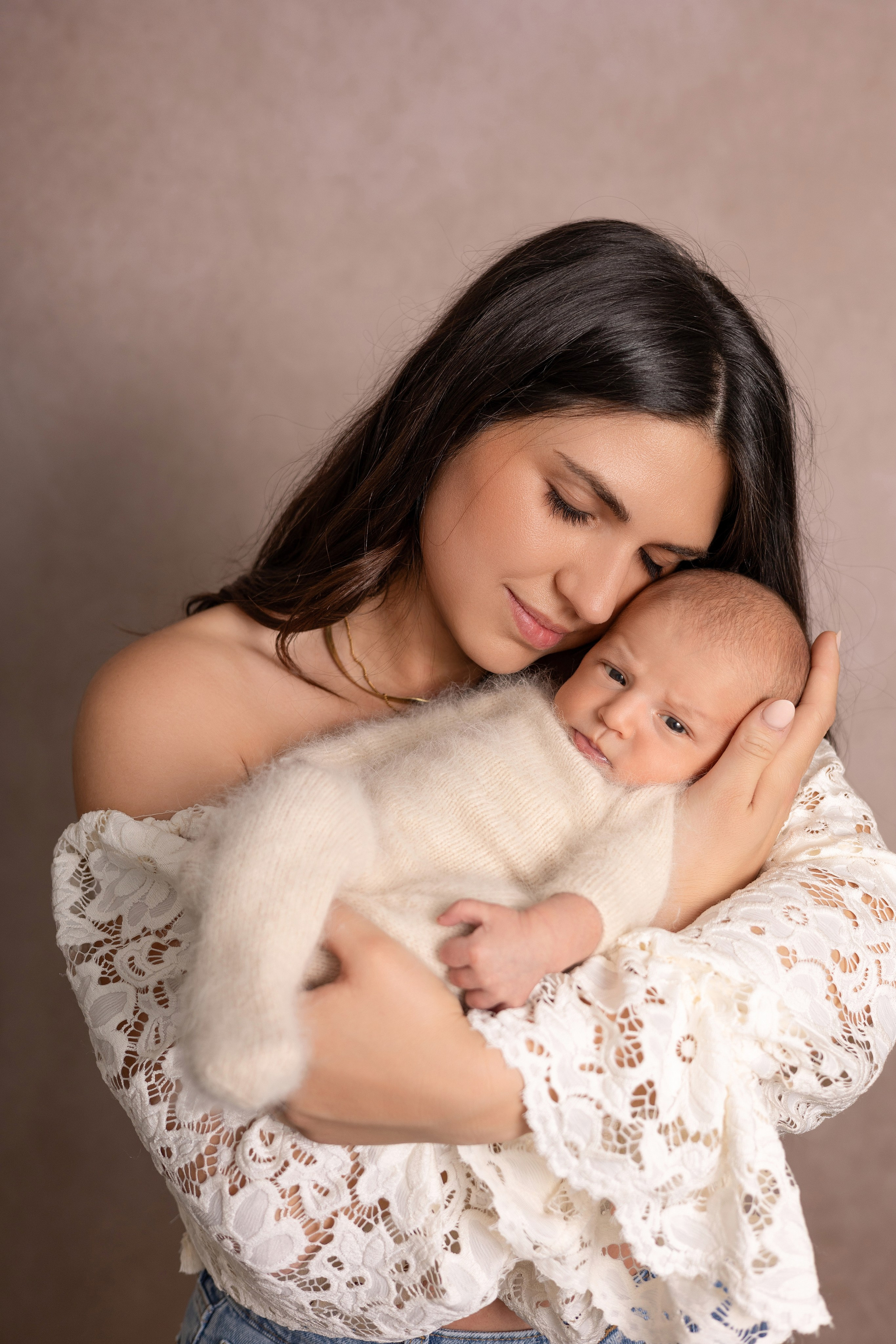 Emotionale Aufnahme einer Mutter, die ihr Neugeborenes liebevoll küsst – Babyfotoshooting in Iserlohn.
