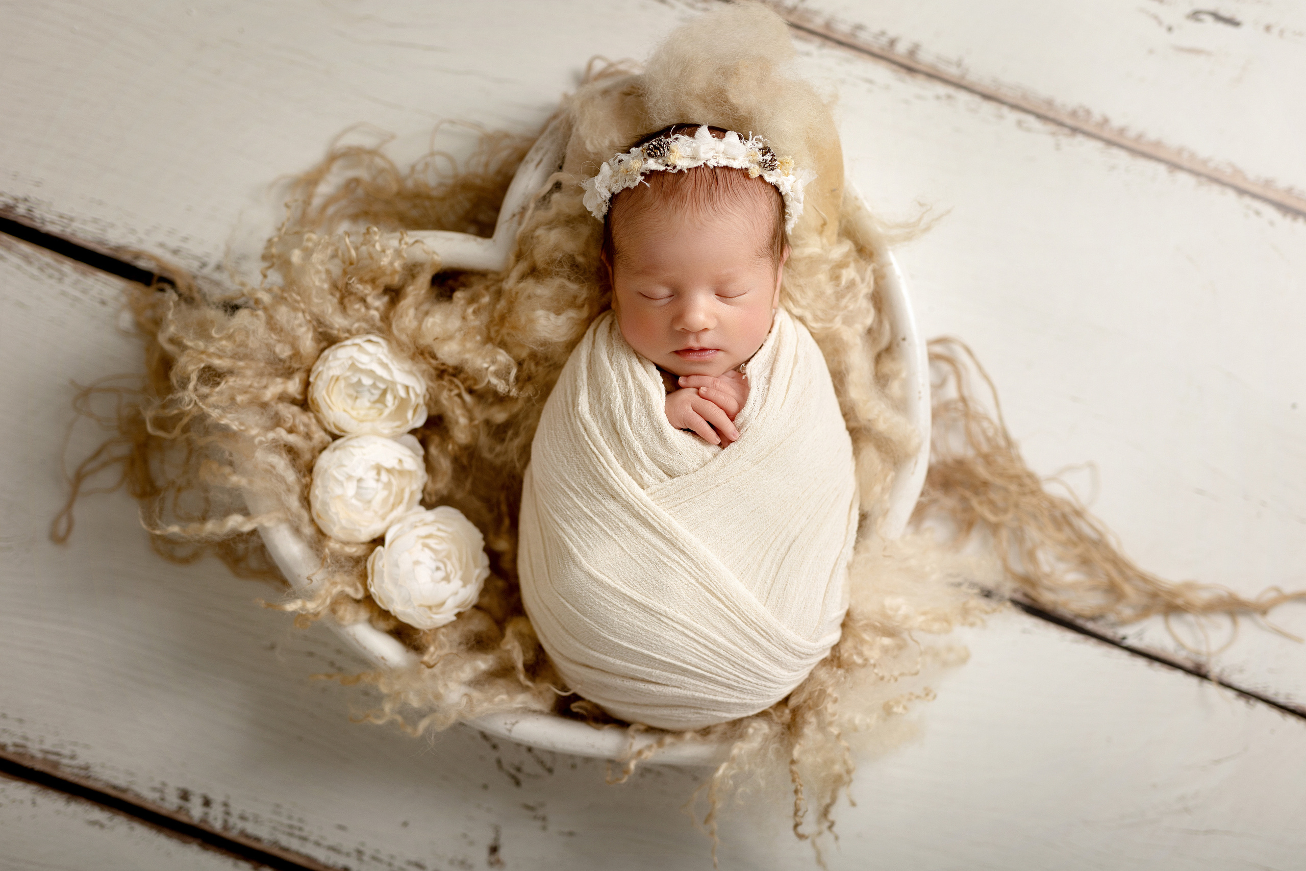 Frisch geborenes Baby eingewickelt in eine Decke, liegt in einem rustikalen Körbchen – Newbornfotografie in Iserlohn