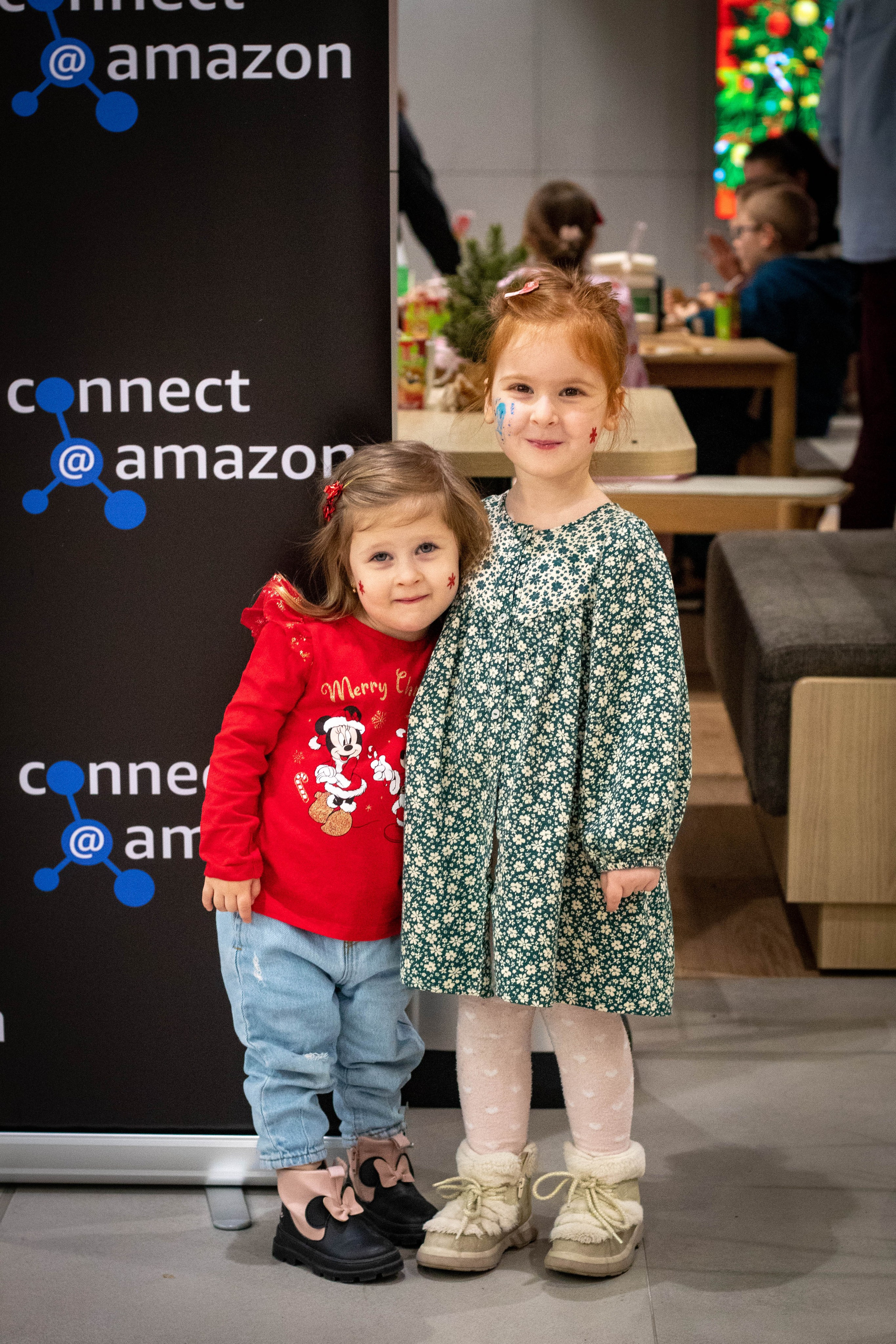 Little girl in a green dress smiling indoors during a festive holiday event.
