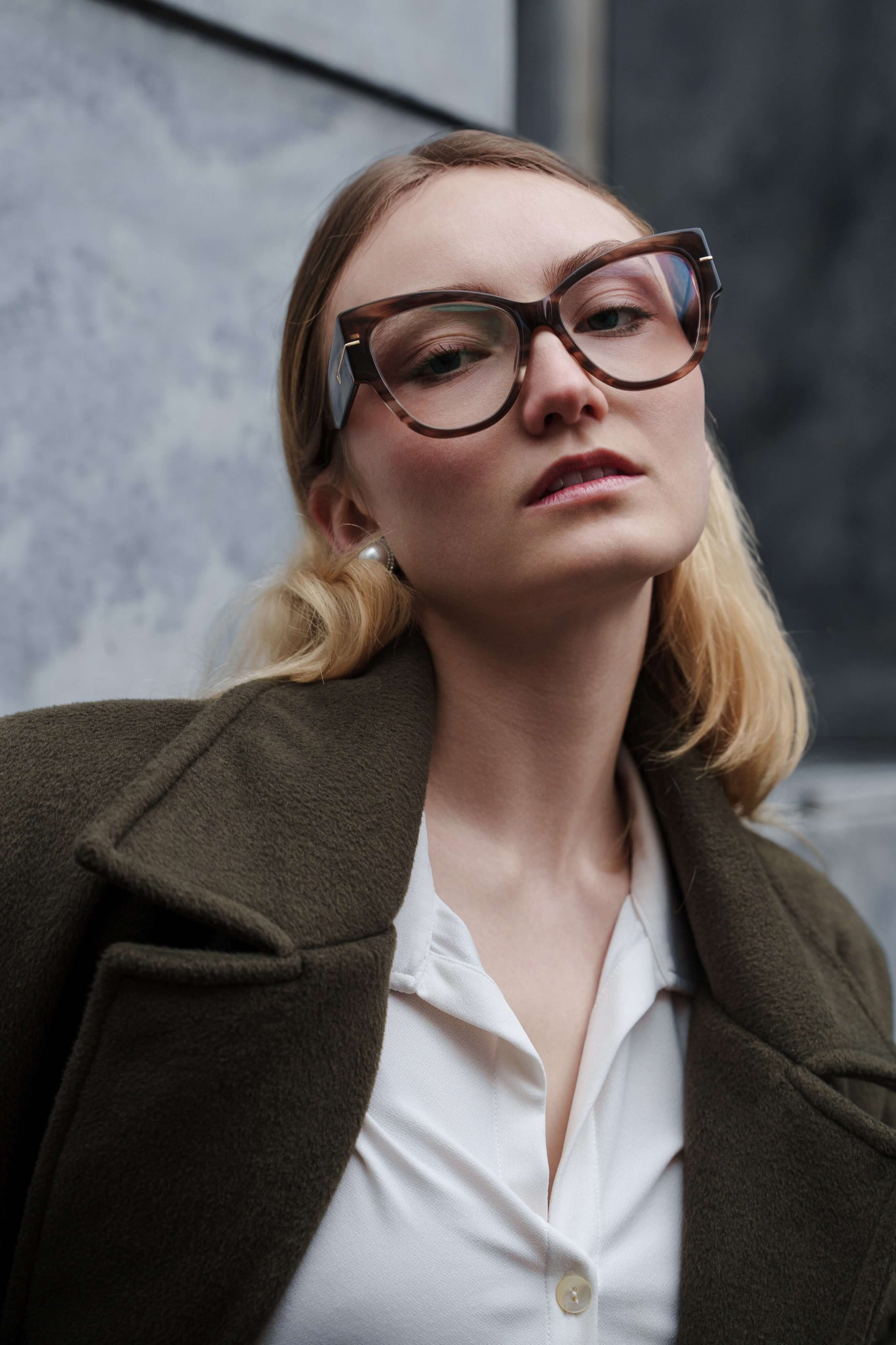 Close-up portrait of woman with oversized glasses and a confident expression
