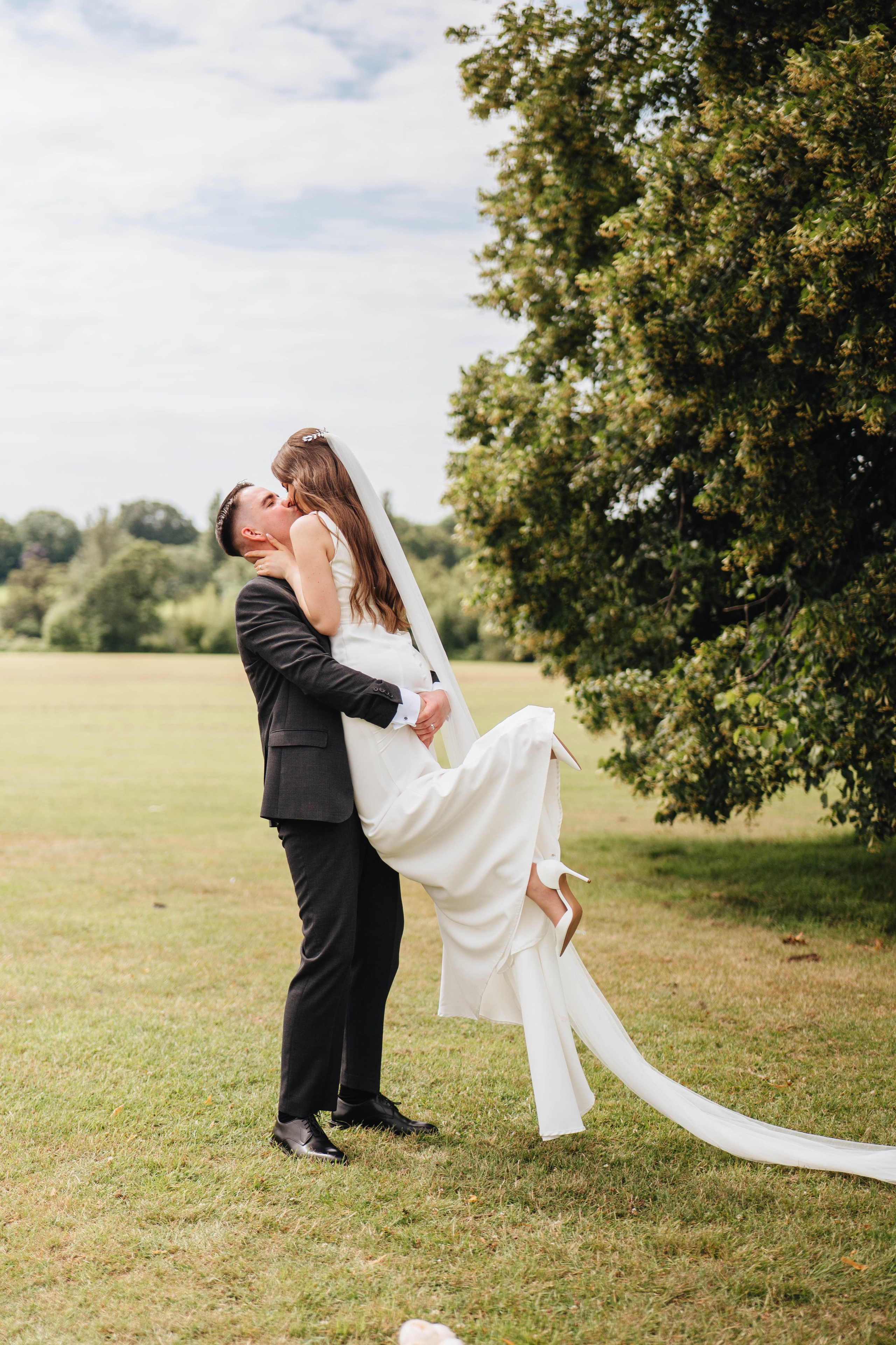 groom holding the bride in hands in the park and kissing