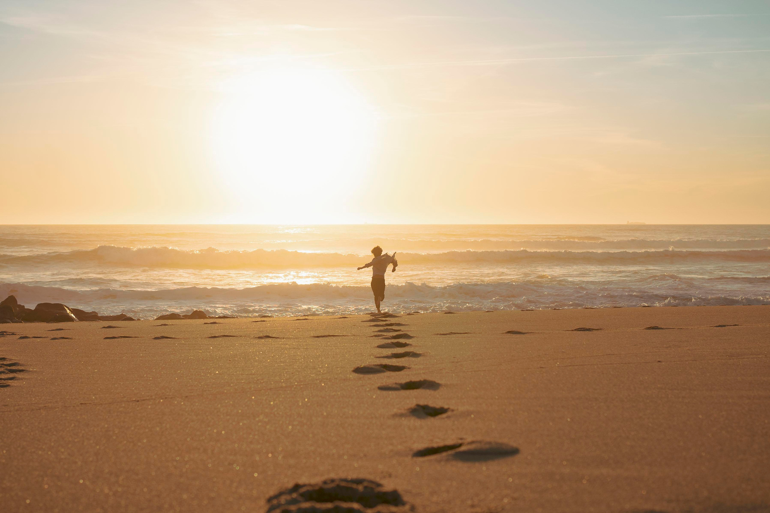A person running into the sunset on an ocean beach. Sunset on the ocean.