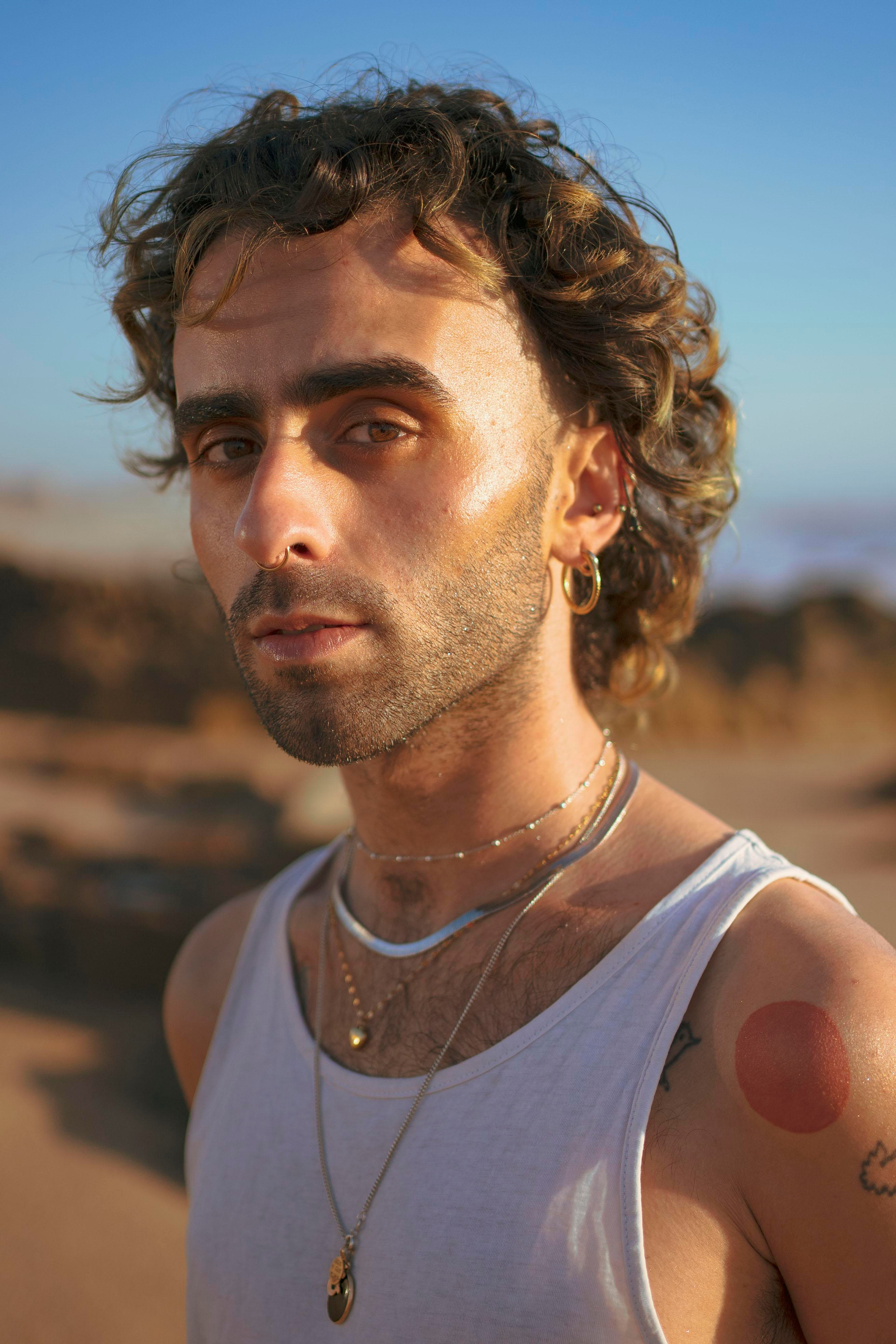 LGBTQ+, LGBT portrait of a beautiful person with makeup, a white tank top, and curly hair.  
