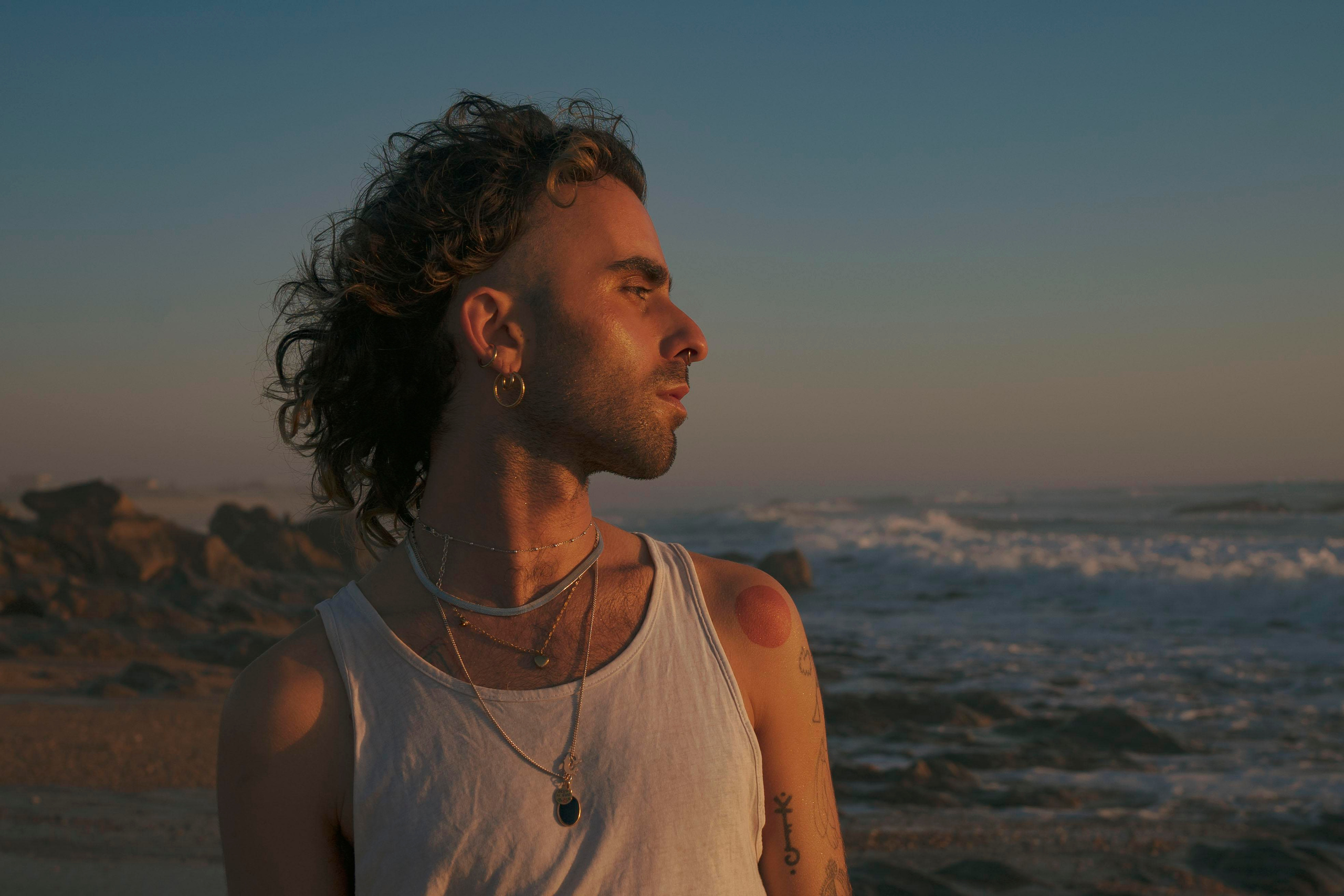 LGBTQ+, LGBT portrait of a beautiful person with makeup, a white tank top, and curly hair.