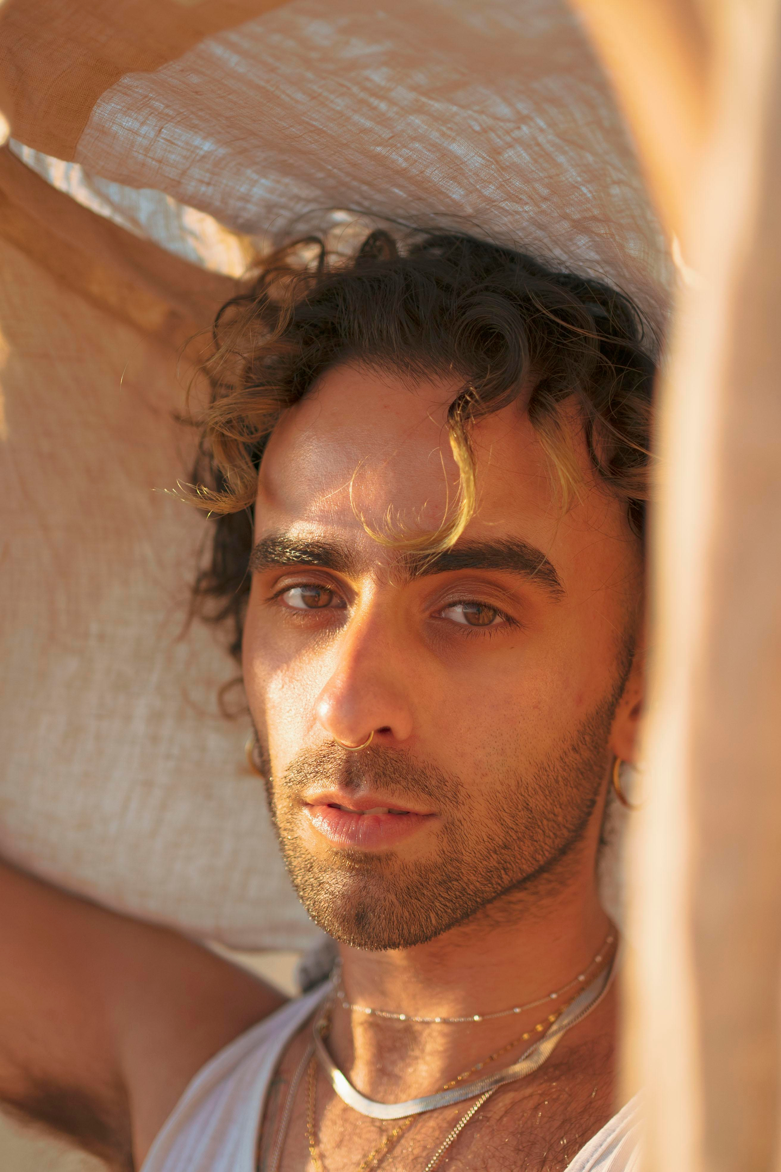 LGBTQ+, LGBT portrait of a beautiful person with makeup, a white tank top, and curly hair.