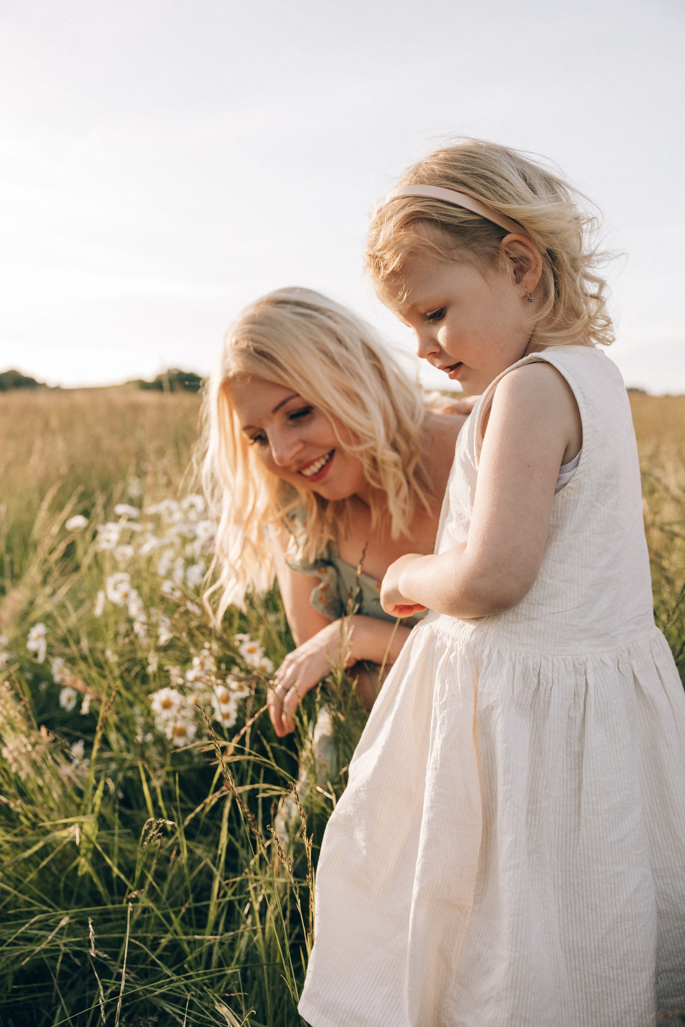 Family photoshoot in a daisy meadow at golden hour — natural light, warm tones, candid moments between a mother and her daughters. Lifestyle and Family Photographer in Pisek Oxana Telupilova