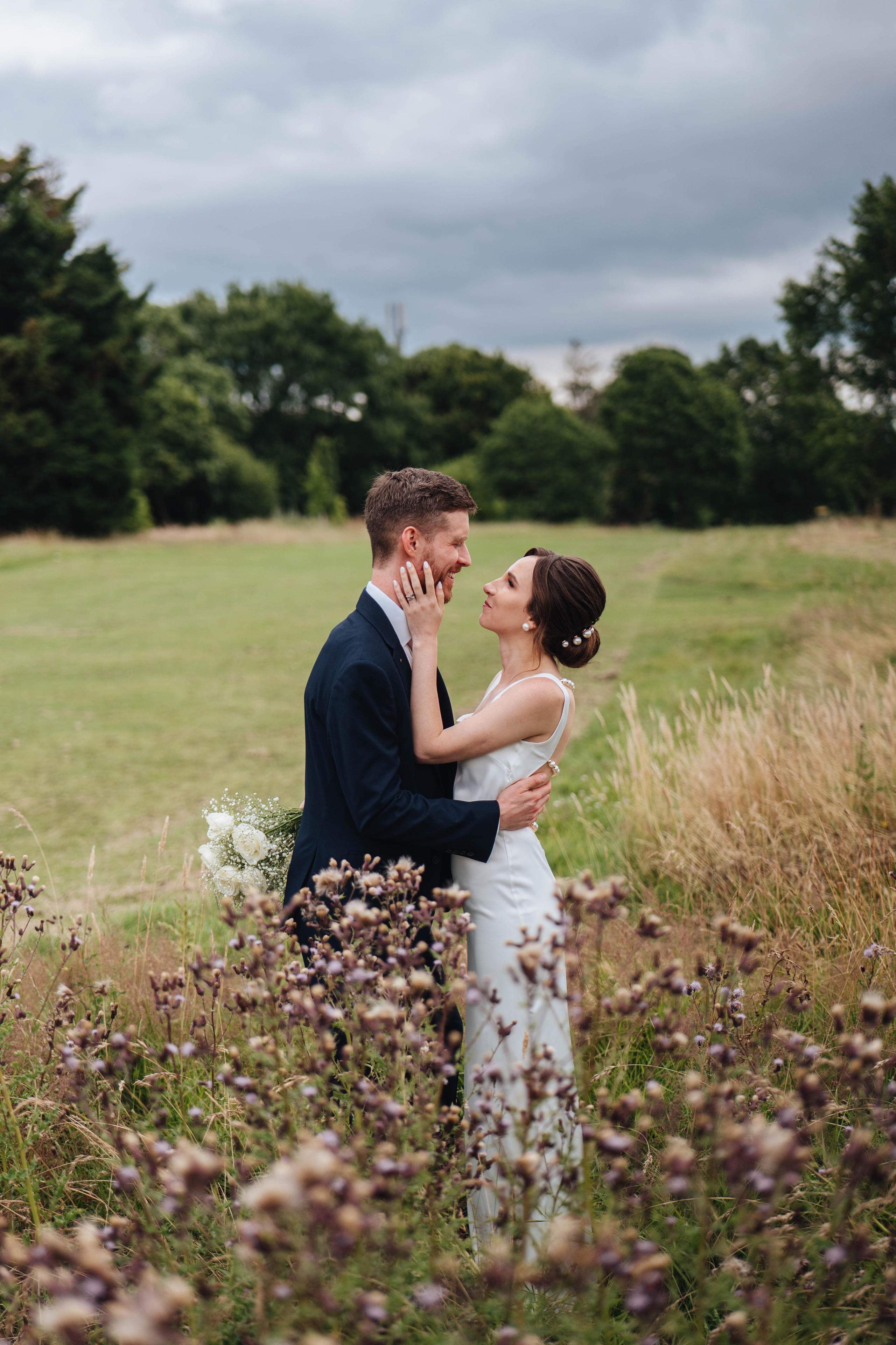 moody photo of bride and groom are looking at each other in fields