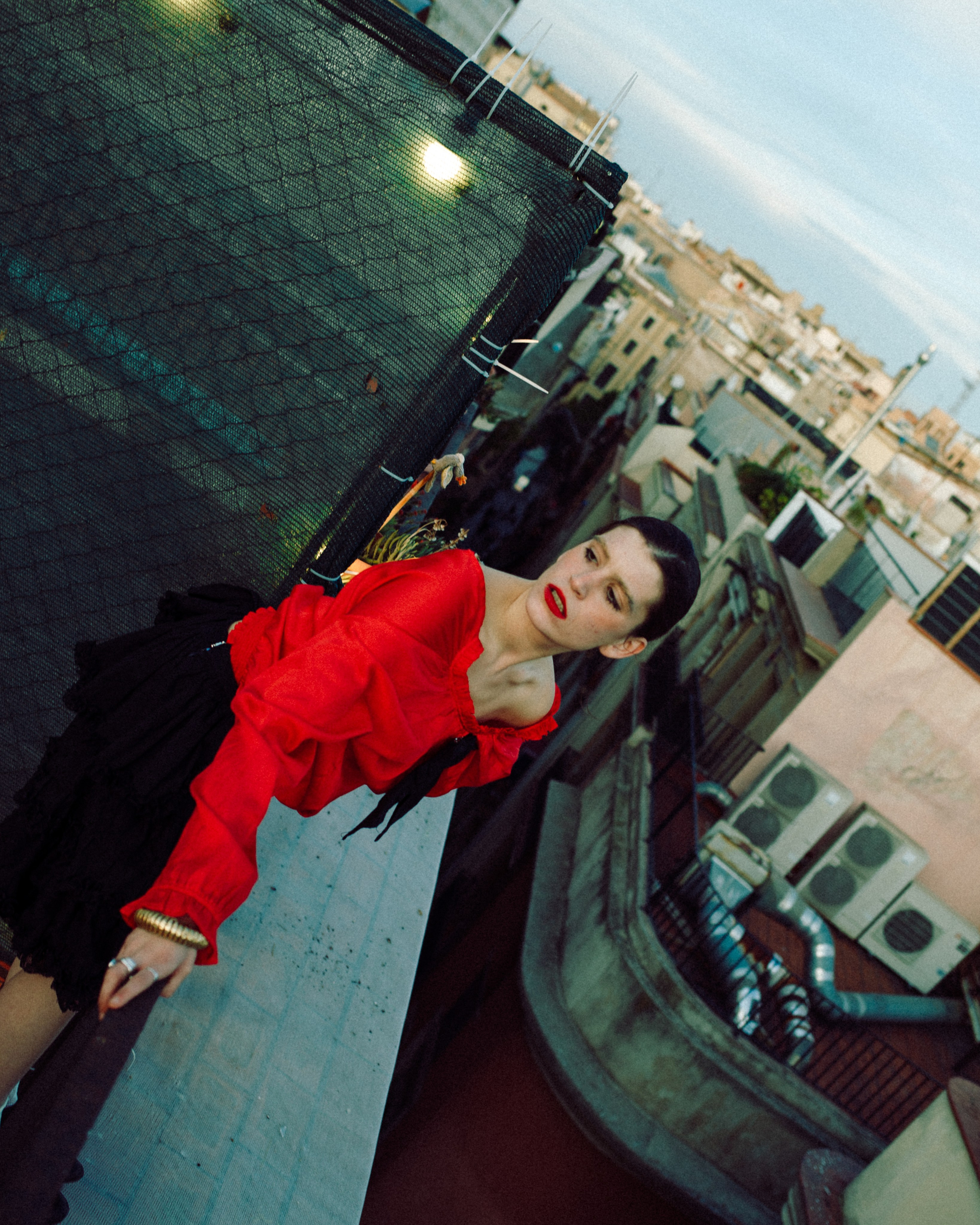 Woman leaning on a rooftop railing, cityscape in the background