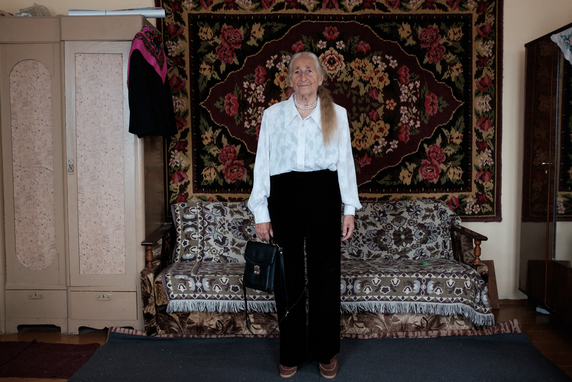 Vera is standing in trousers, which she bought when she was in hospital because there all women were in trousers. Normally Vera doesn't wear trousers. She assumes that for her fits more skirts and dresses. 