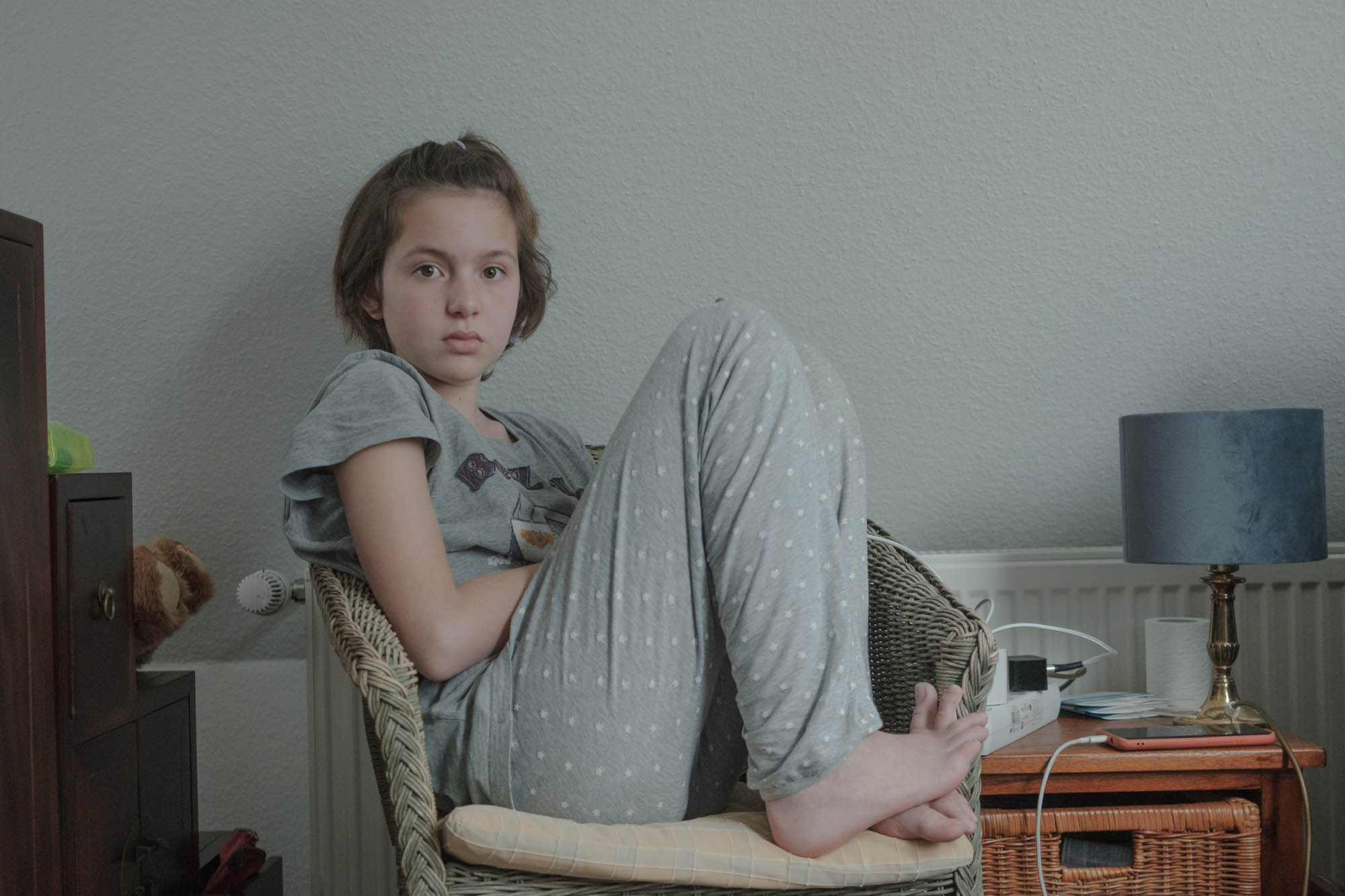 Sabrina is sitting on the bed in the room where she lives with her parents in Julia and Max’s house, April, 2022