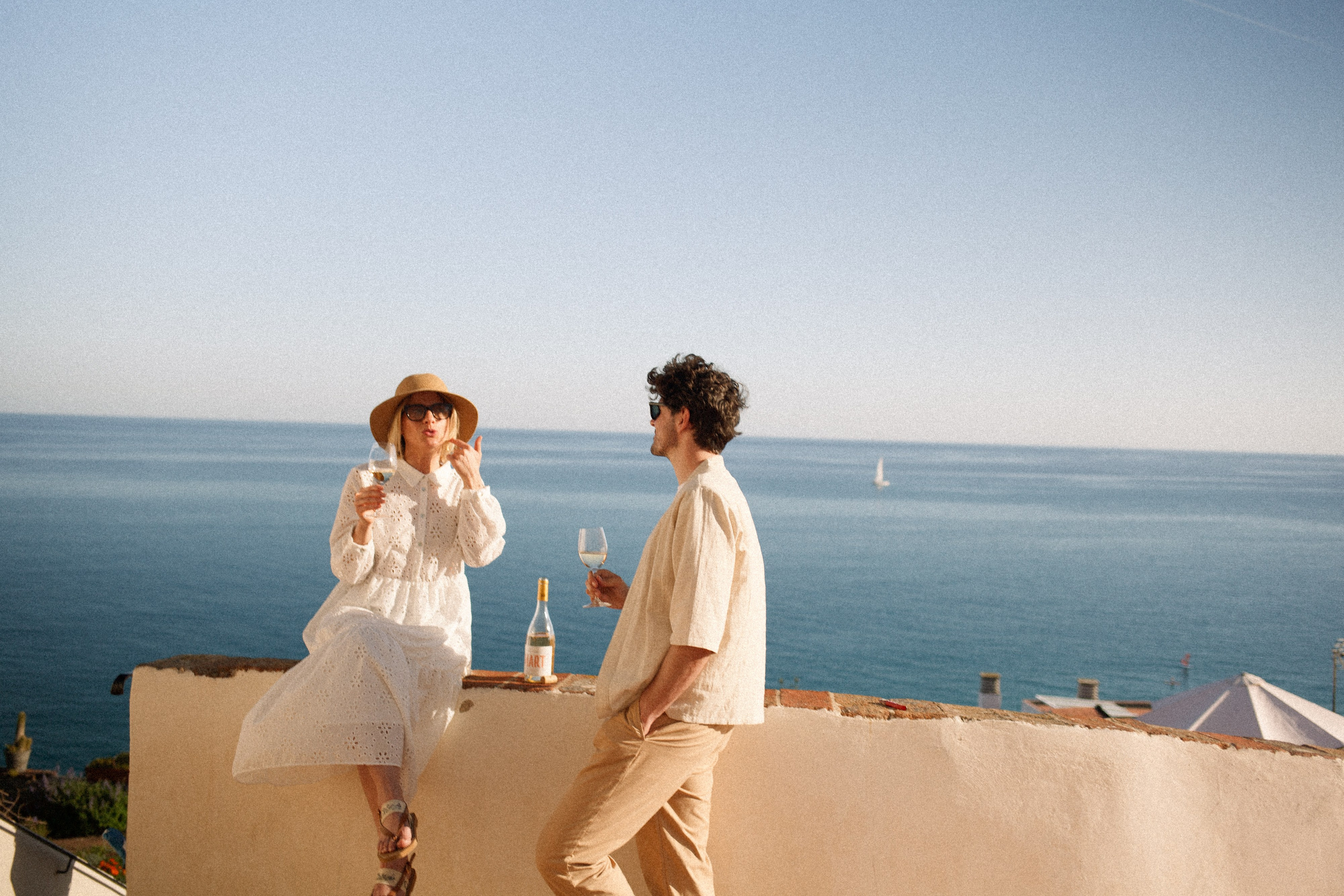 Smiling couple sharing Mart wine with a scenic sea view from the top