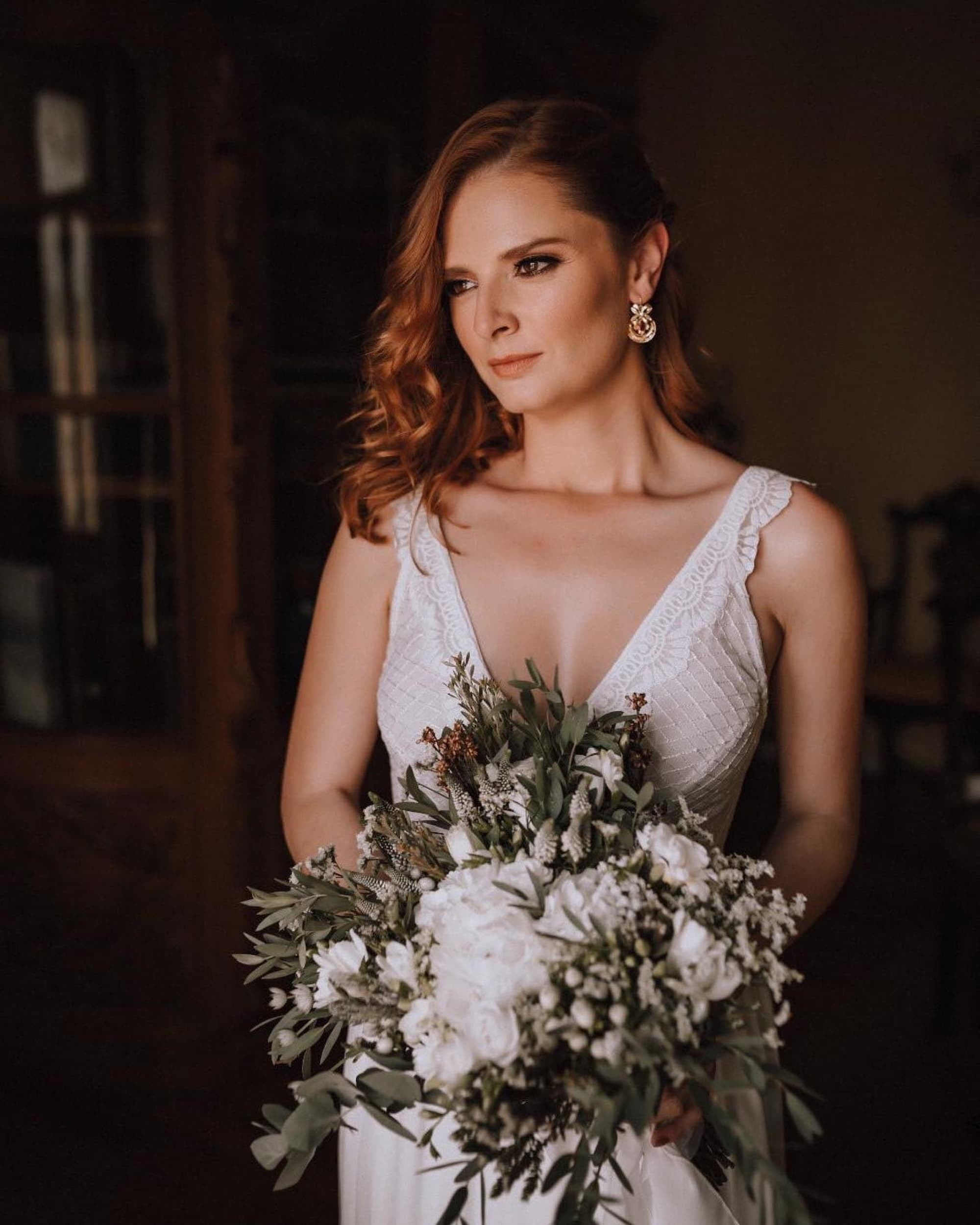 Retrato clássico de noiva com bouquet branco e ar contemplativo num espaço elegante em Guimarães.