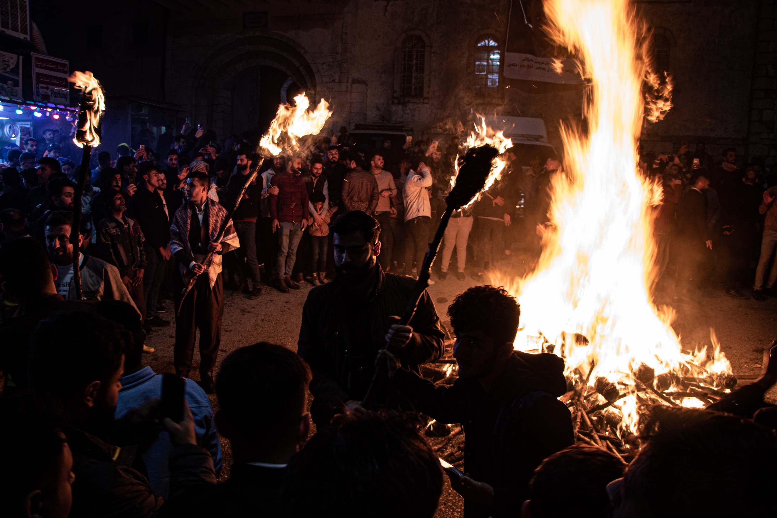 Des torches sont allumées autour d’un grand feu lors des célébrations du Nouvel An kurde à Akre, marquant un moment fort de la fête traditionnelle de Nowruz.