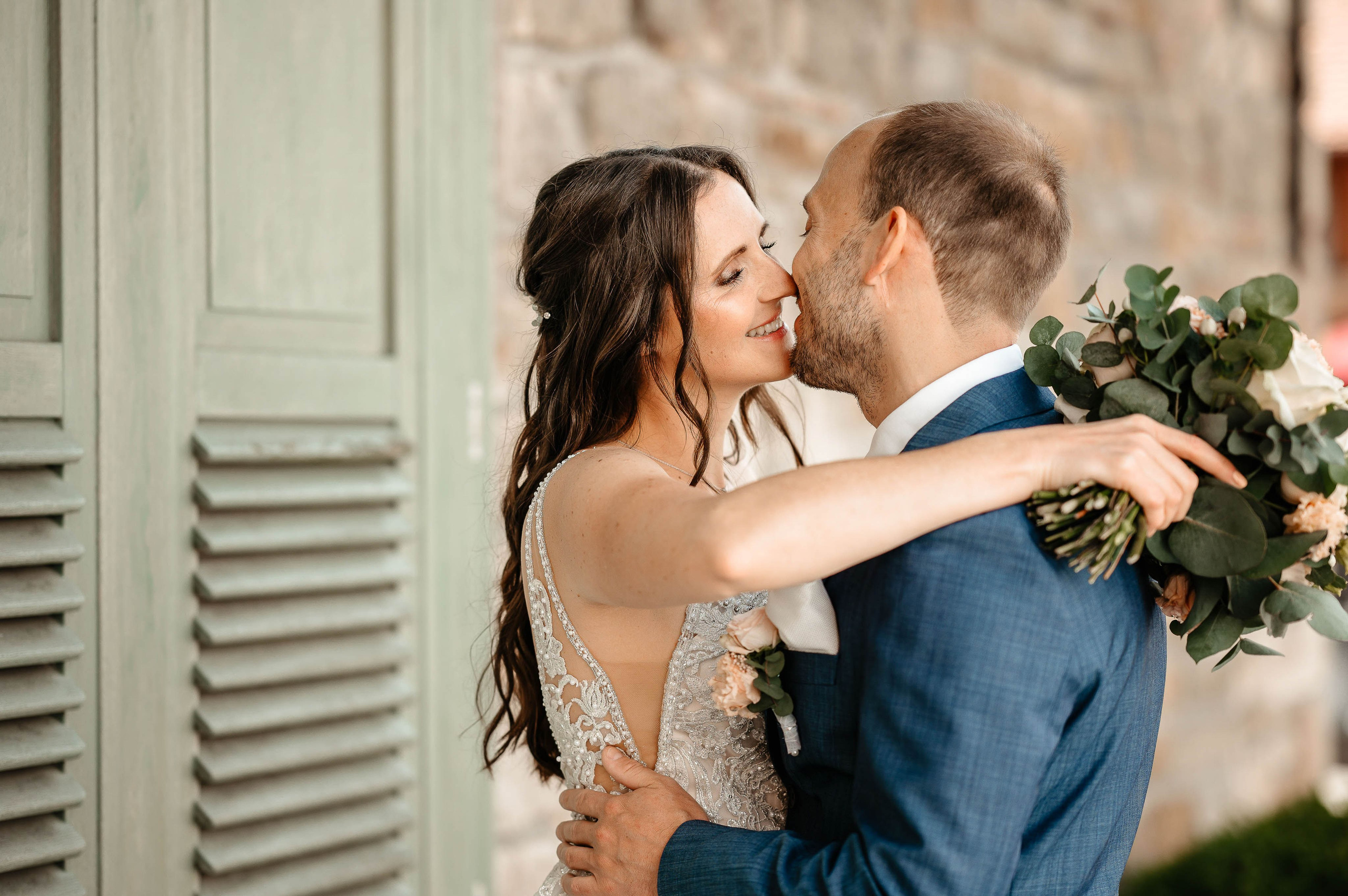 Hochzeitsfotograf Paar intimer Kuss, Braut und Bräutigam mit Blumenstrauß.