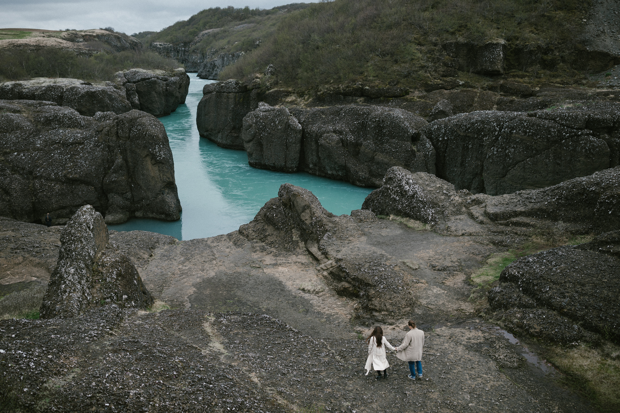 Wedding photo session holding hands near turquoise river canyon in Iceland