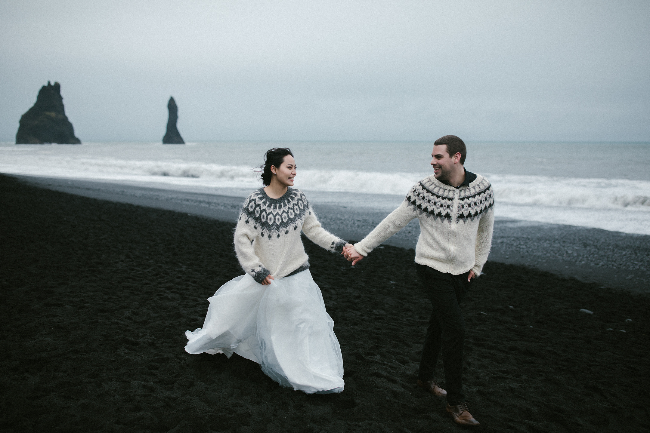 Lachendes Paar läuft am schwarzen Sandstrand von Reynisfjara