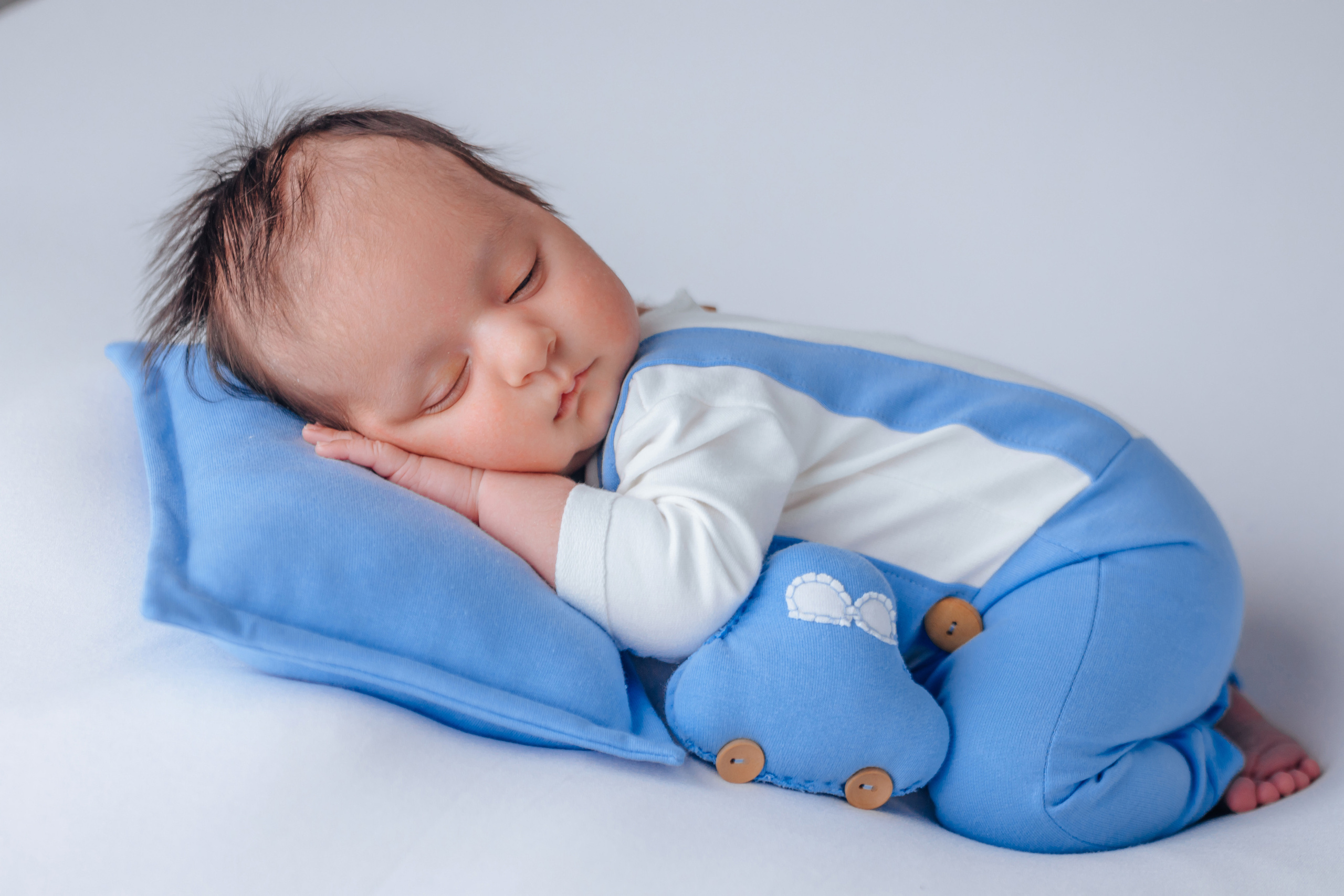 Babyjunge auf blauer Decke mit Spielzeugauto – professionelles Babyshooting München