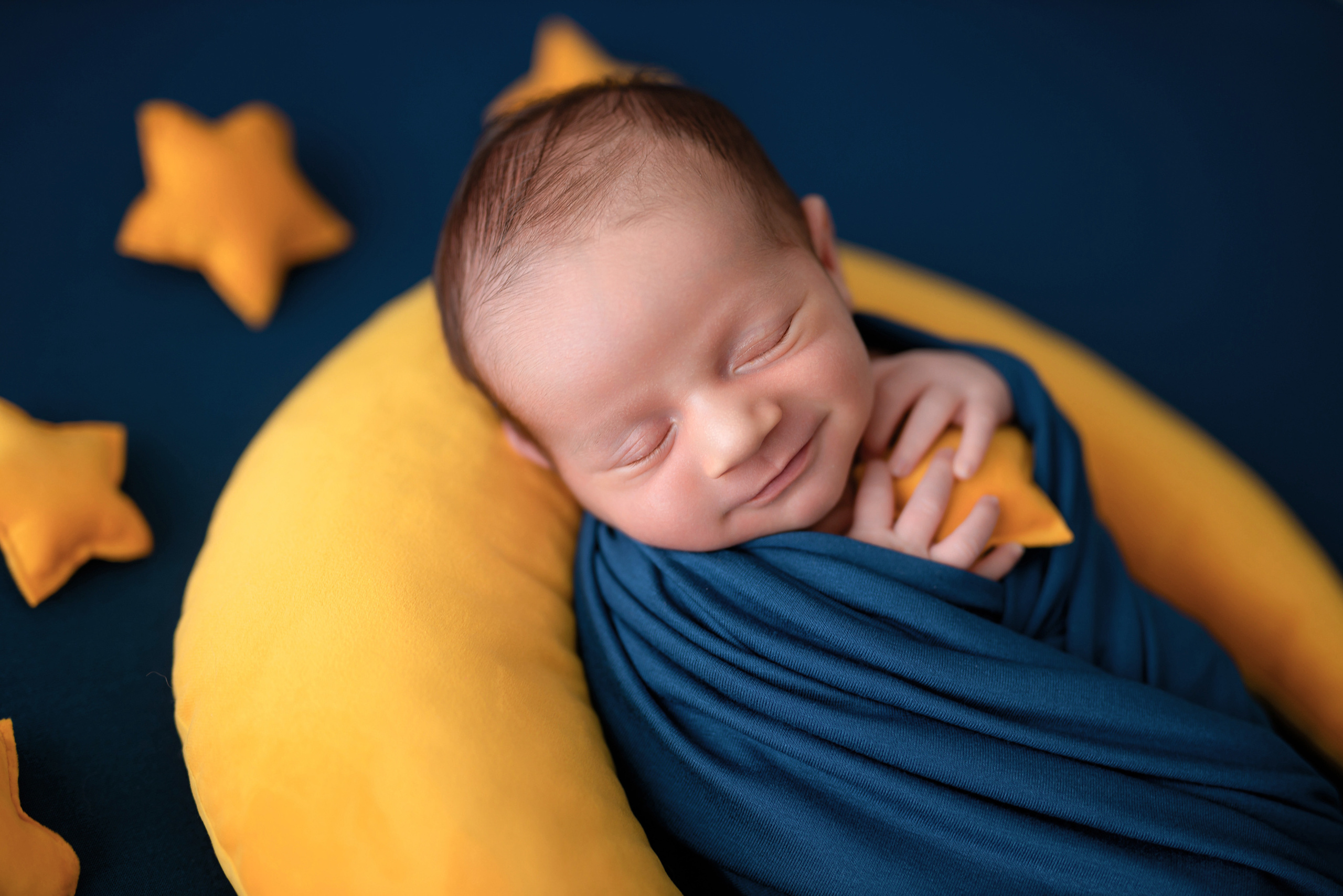 Neugeborenes auf Mondsichel mit gelben Sternen – kreative Newbornfotografie in Karlsfeld