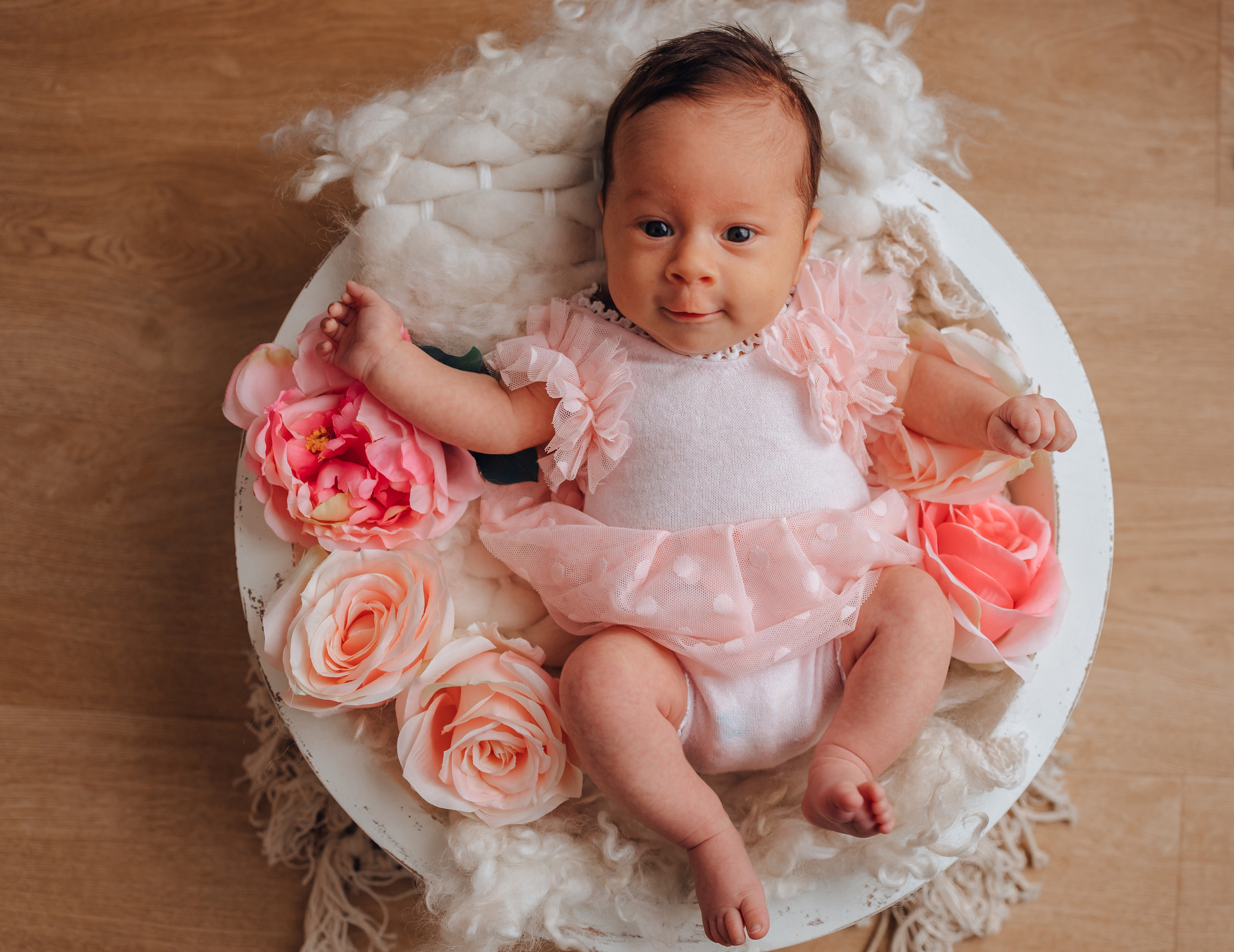 Neugeborenes Mädchen im runden Holzkörbchen mit Blumen – natürliche Babyfotografie