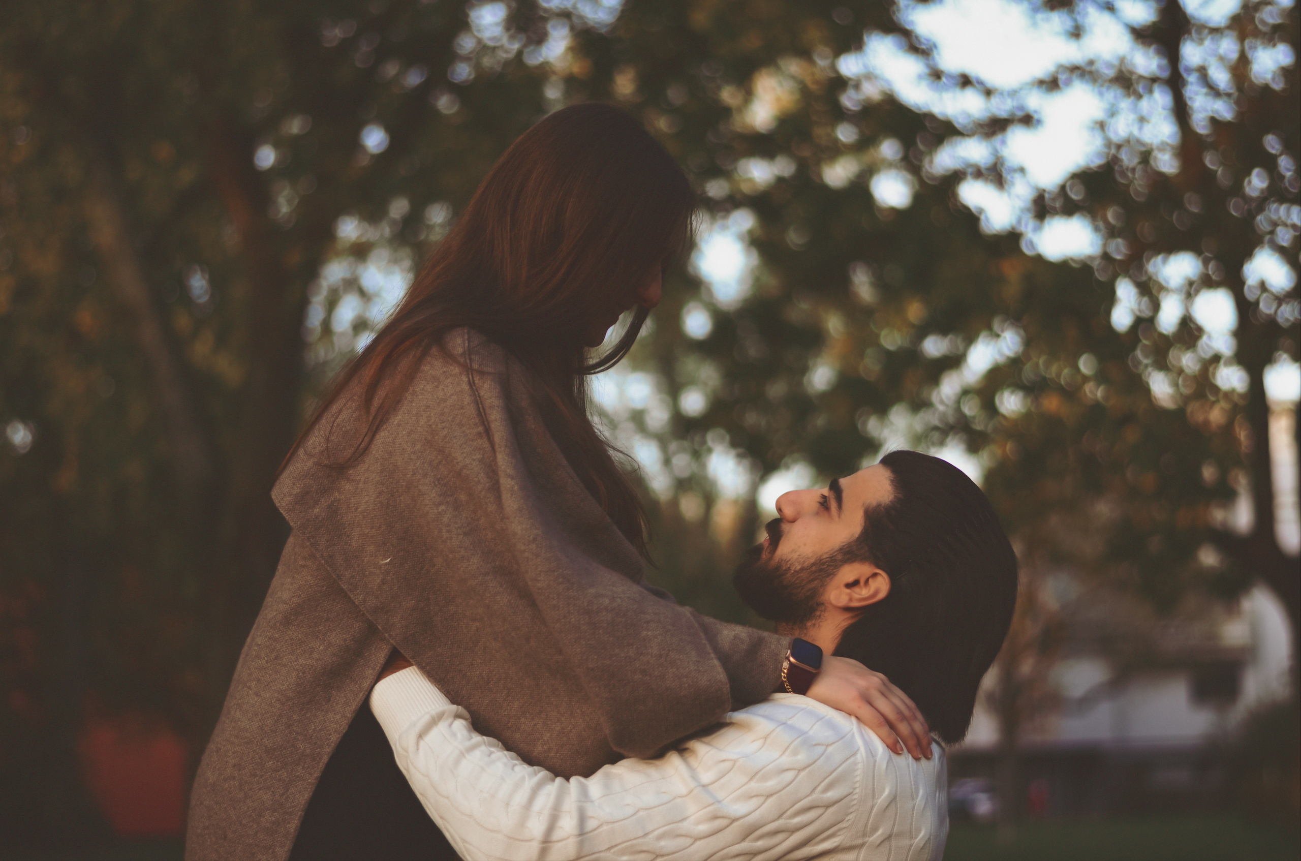 Foto eines verlobten Paares im verträumten, weichen Stil mit Bäumen im Hintergrund