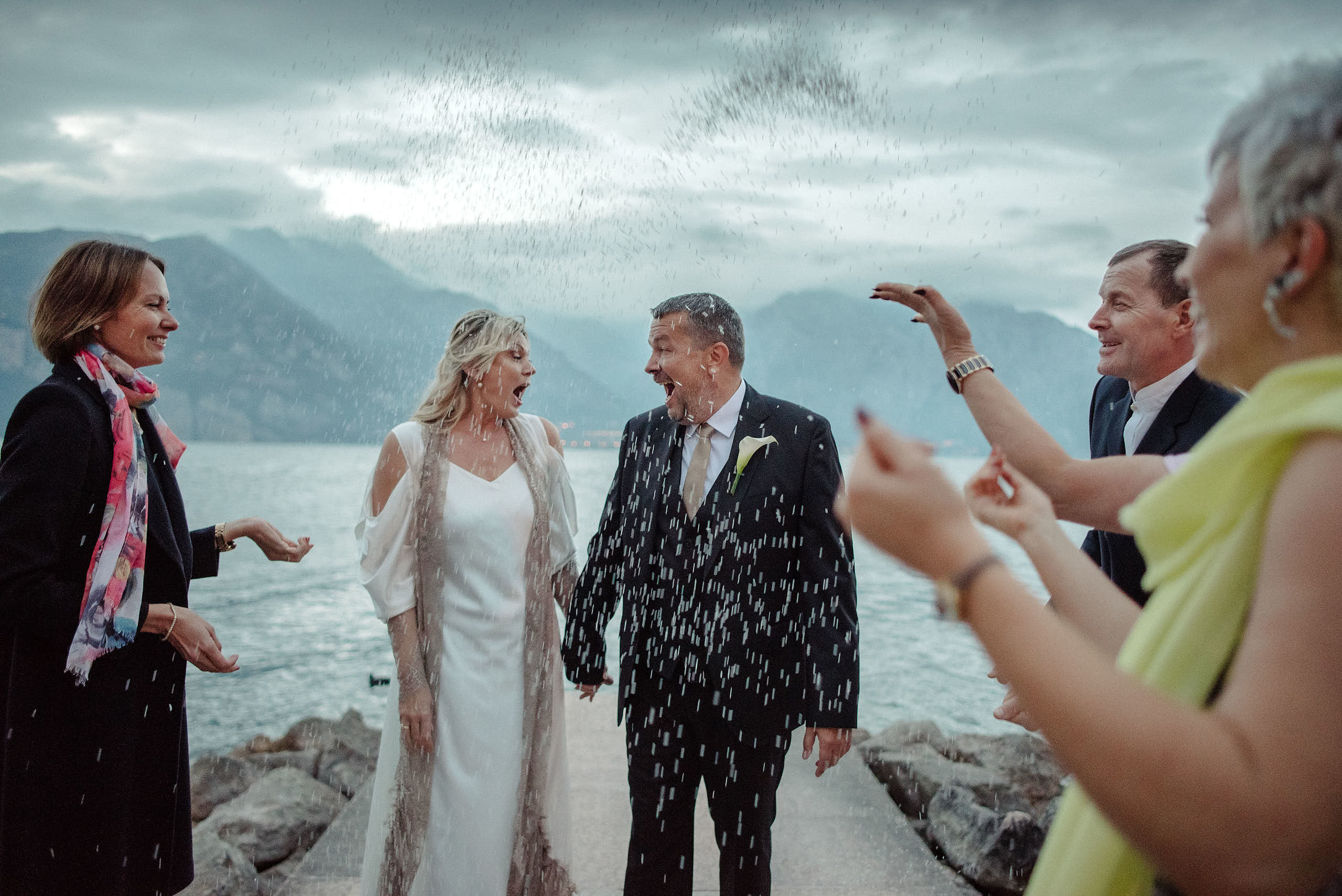  La Sposa con bellissimo  lo sposo durante il lancio del riso in Malcesine dopo matrimonio. Fotografo di Matrimonio sul lago di Garda.