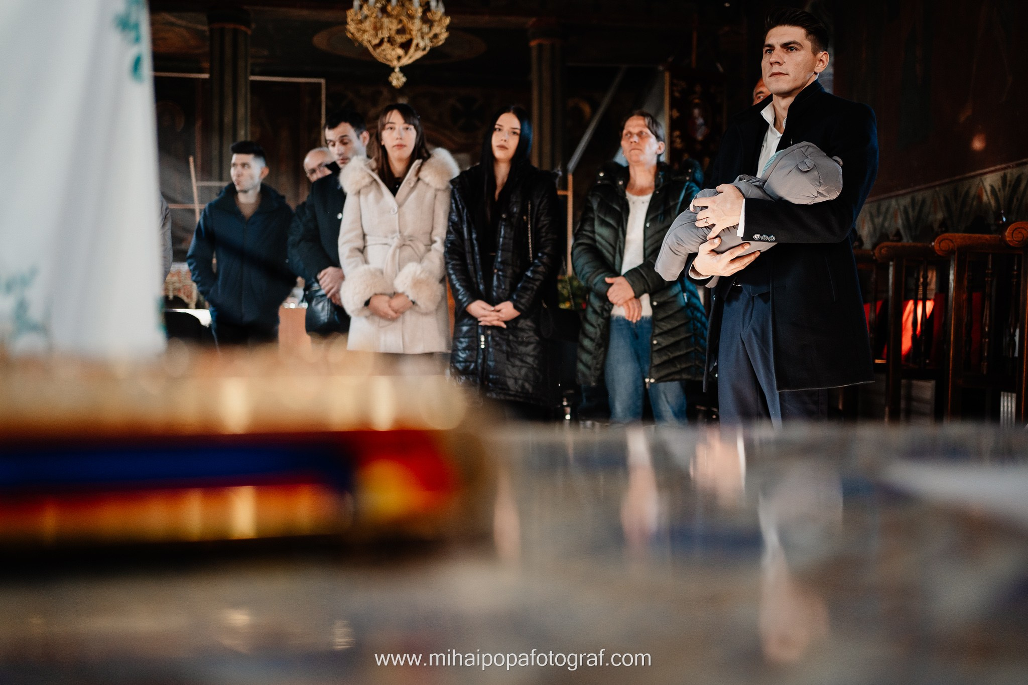 Instantaneu plin de tandrețe dintre părinți și bebeluș în ziua botezului, realizat în ilfov. Fotografie profesională de botez, capturând emoțiile autentice ale familiei într-un decor luminos și cald