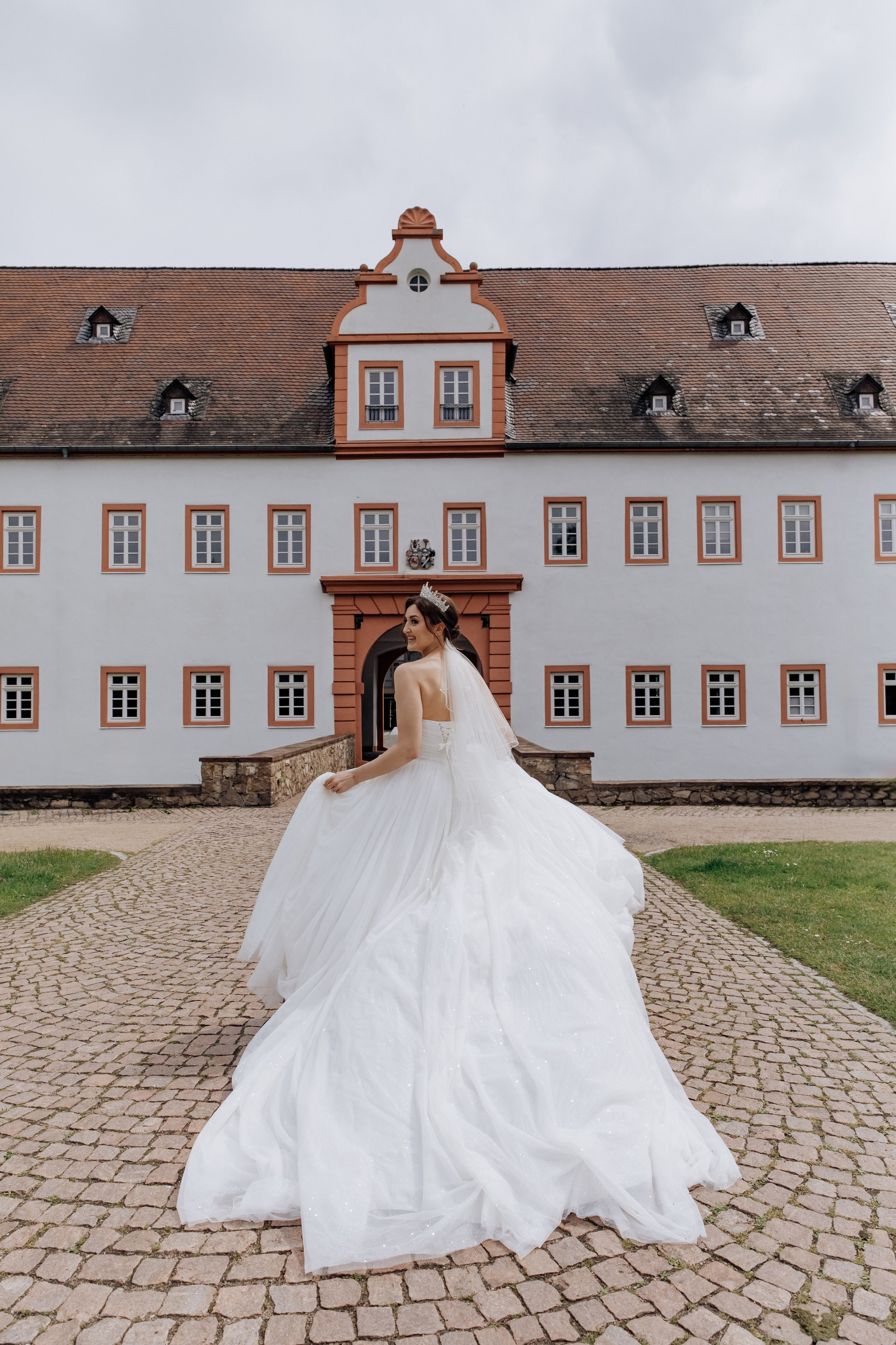 Die Braut läuft auf die Tore des Schlosses Heusenstamm zu und dreht sich dabei zu uns. 