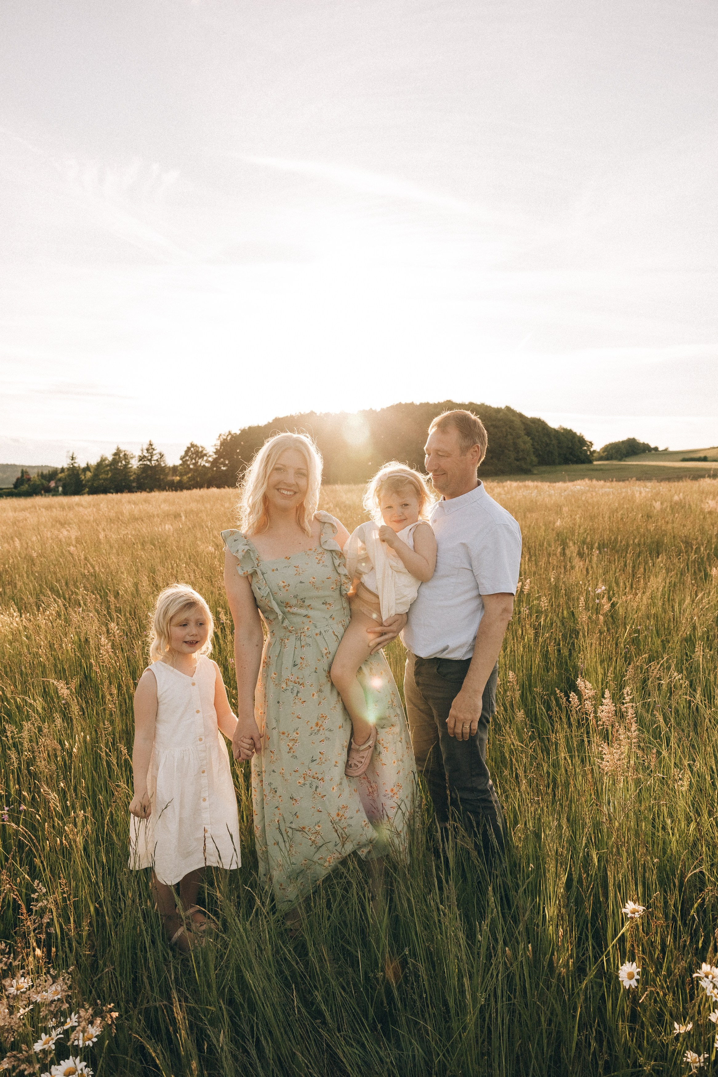 Family photoshoot in a daisy meadow at golden hour — natural light, warm tones, candid moments between a mother and her daughters. Lifestyle and Family Photographer in Pisek Oxana Telupilova