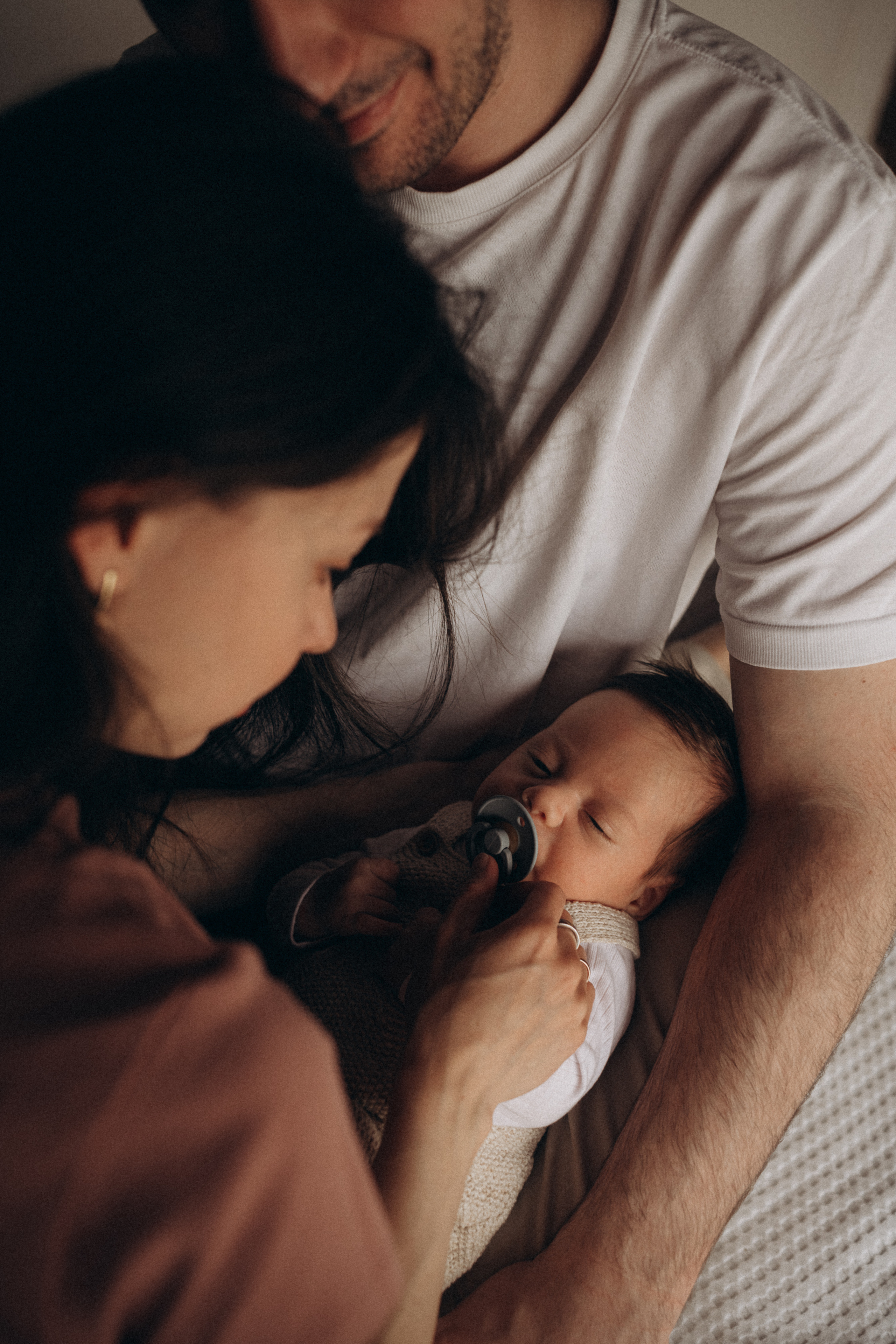 parents hold their sleeping newborn baby