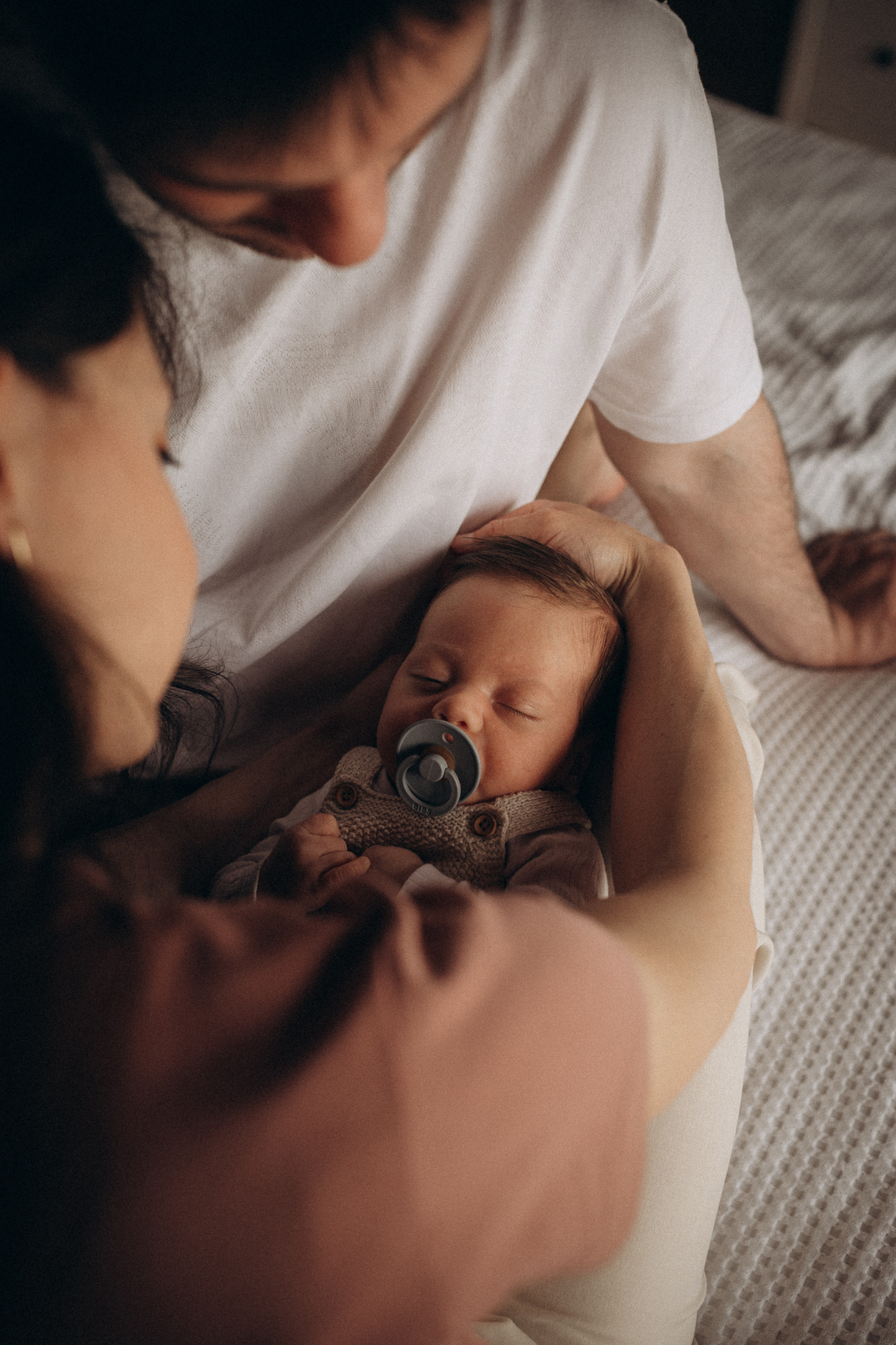 parents look at their sleeping newborn baby