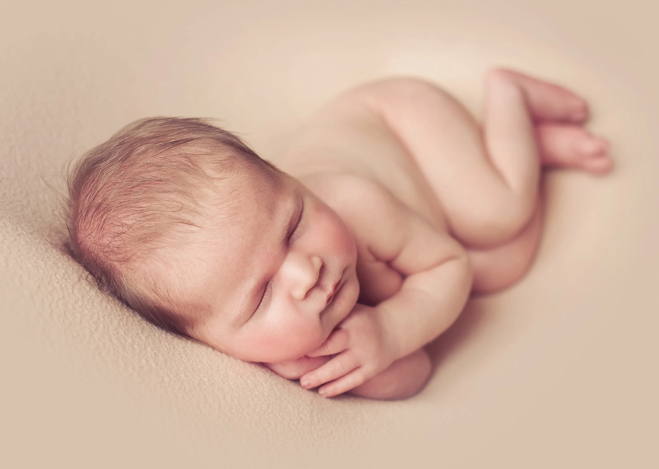 Newborn baby sleeping on side in cozy pose