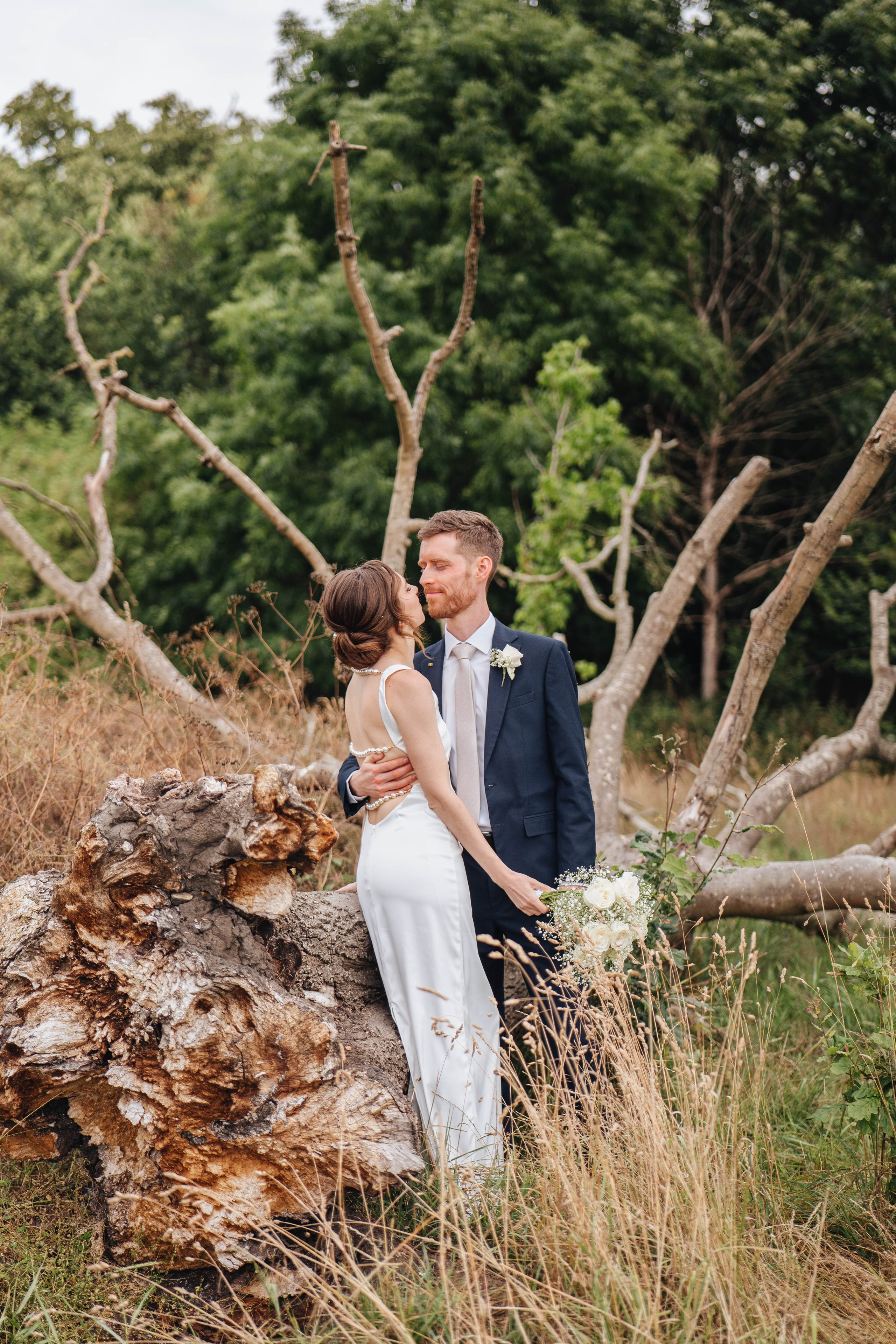 bride and groom posing near an old dead tree