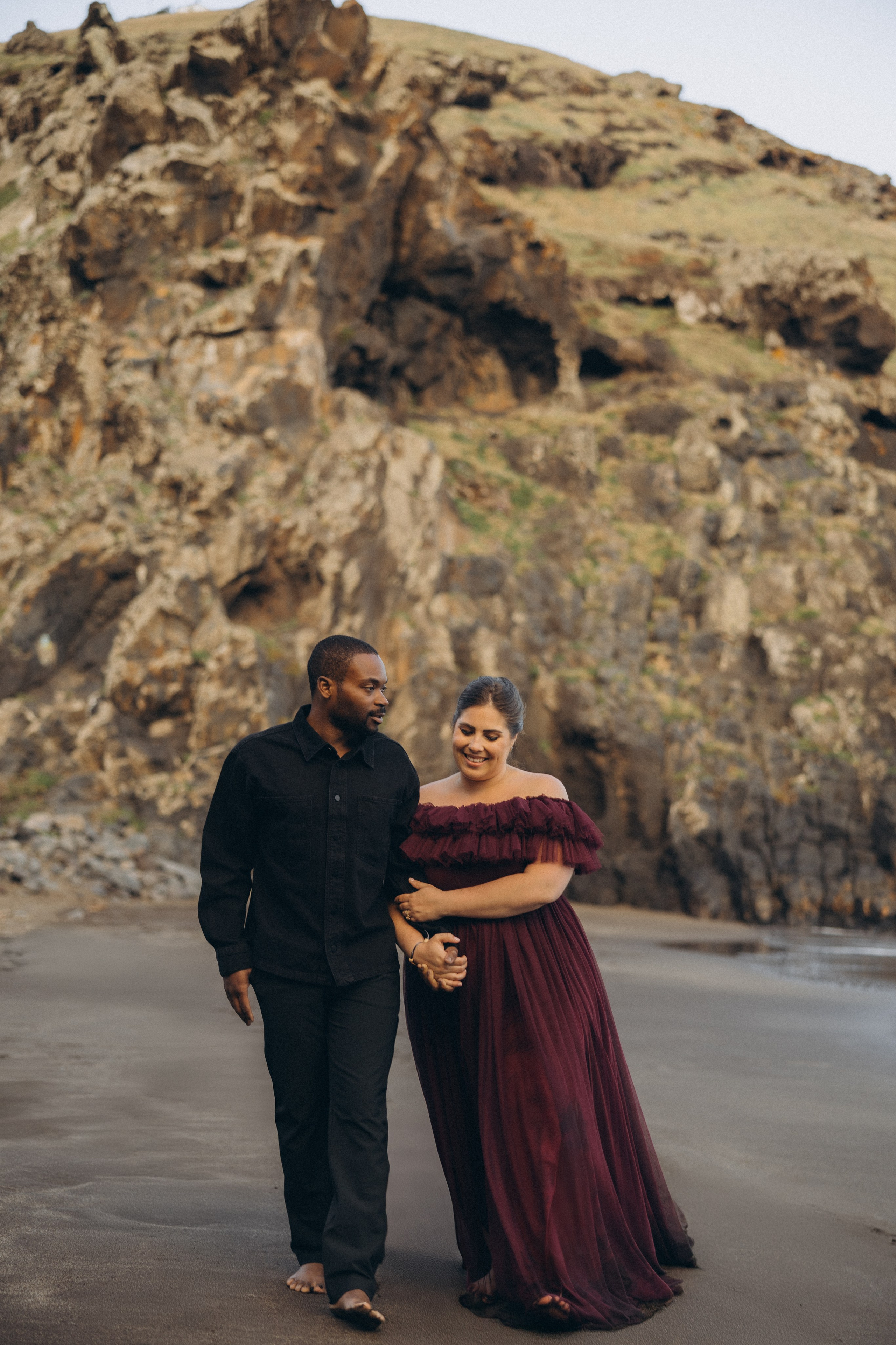 A glowing expectant mother standing on a cliff overlooking the ocean in Madeira, her dress flowing gently in the wind as the golden sunset casts a warm glow.
