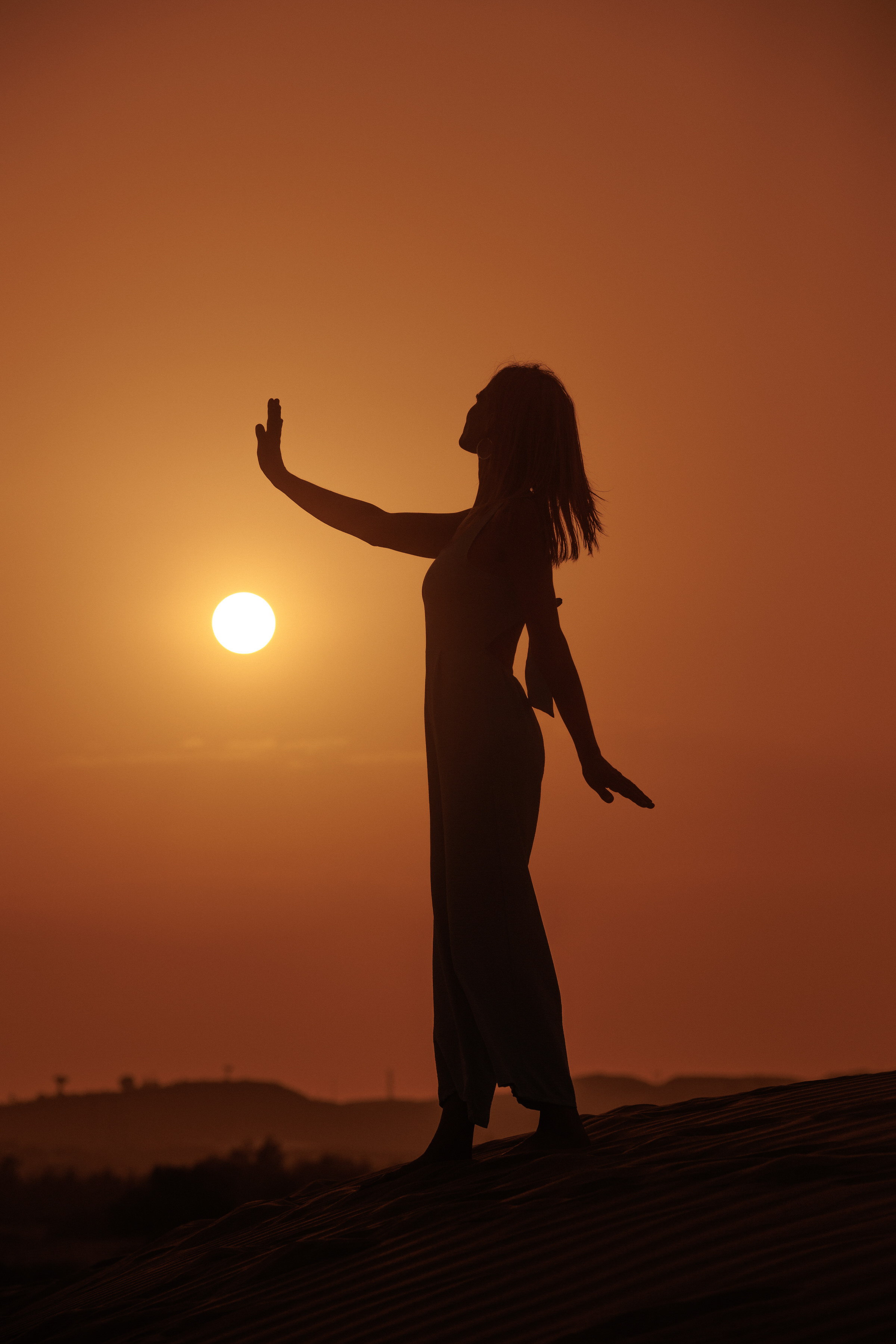 A silhouette of a woman standing on top of a sand dune at sunset Proffessionas photo shoot in Gran Canaria, Maspalomas