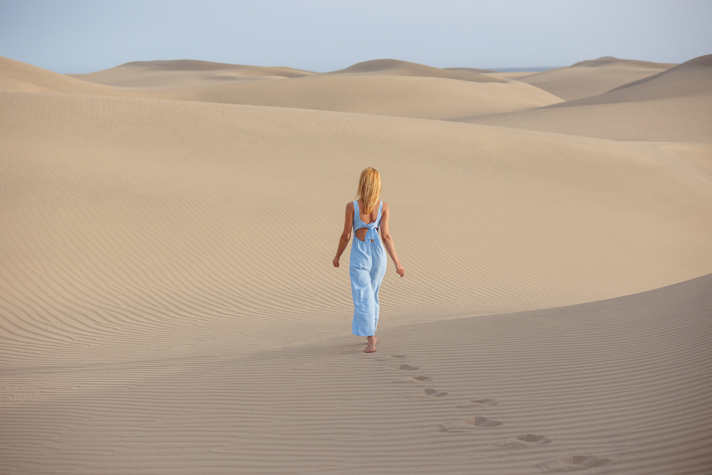 A young woman walking through the sand dunes. With local photographer