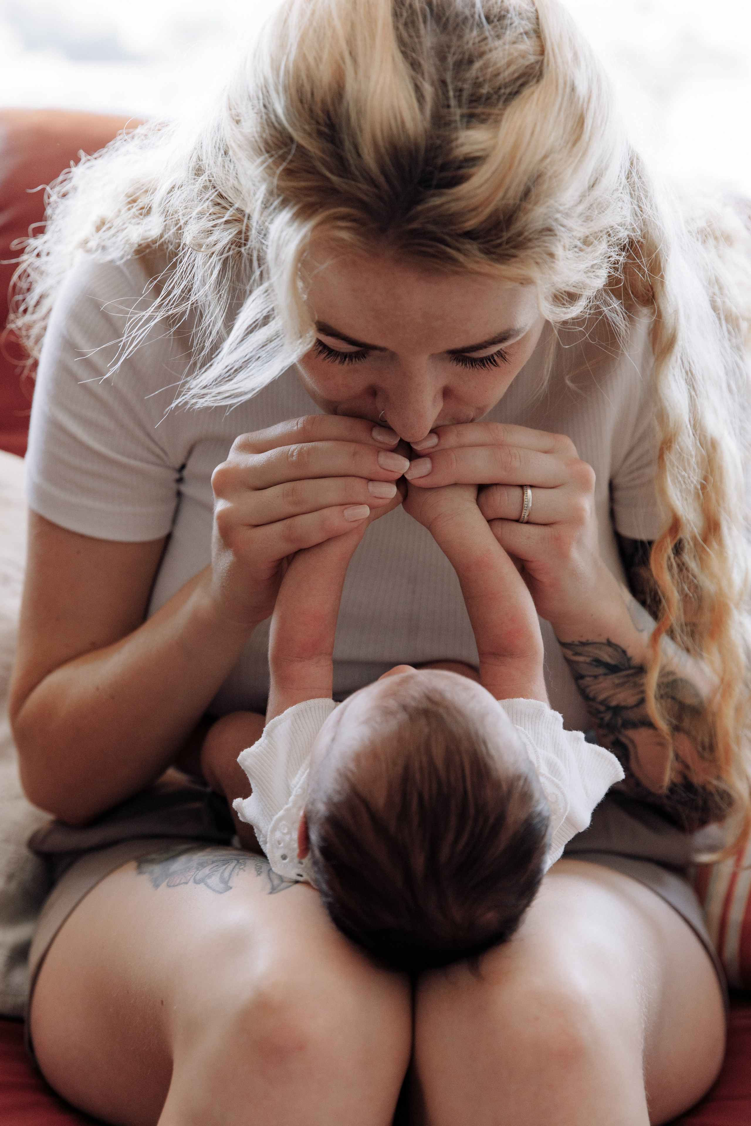 Baby liegt auf dem Schoß der Mutter, die liebevoll ihre Hände küsst.