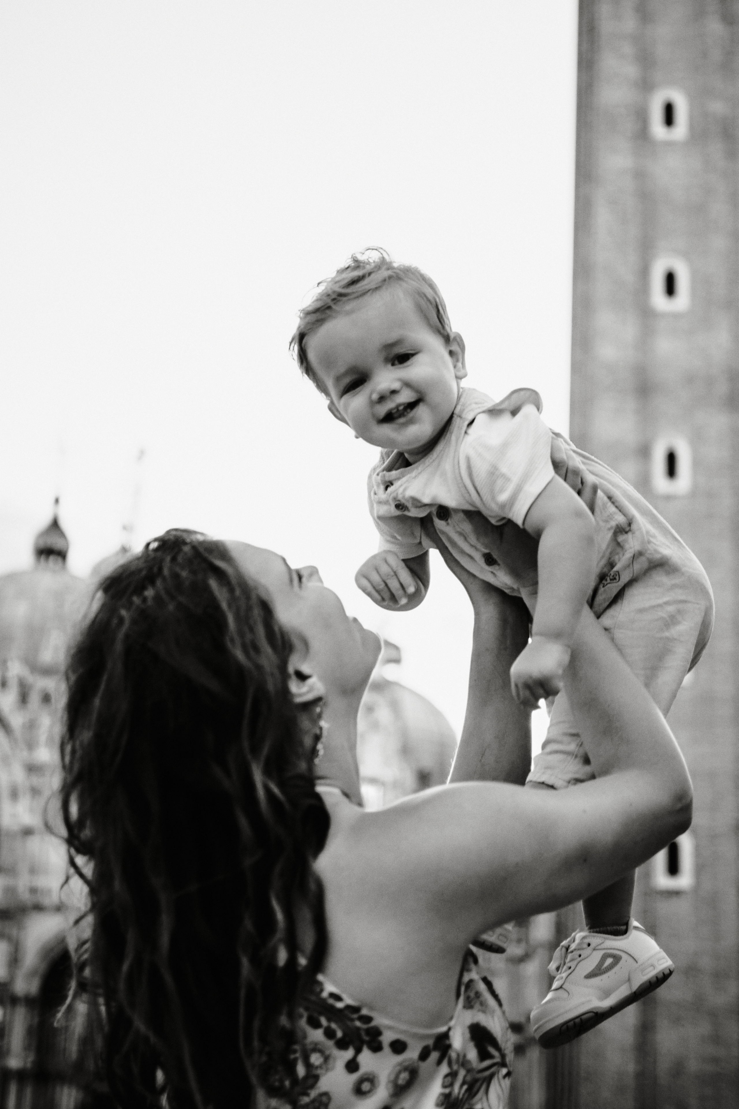 In the heart of Venice, a mother and child share a moment of quiet contemplation on San Marco square. The mother's pregnancy is visible in her gentle curves, while the child's hand rests on her belly, a reminder of the new life growing within. The city's beauty is reflected in their peaceful expressions