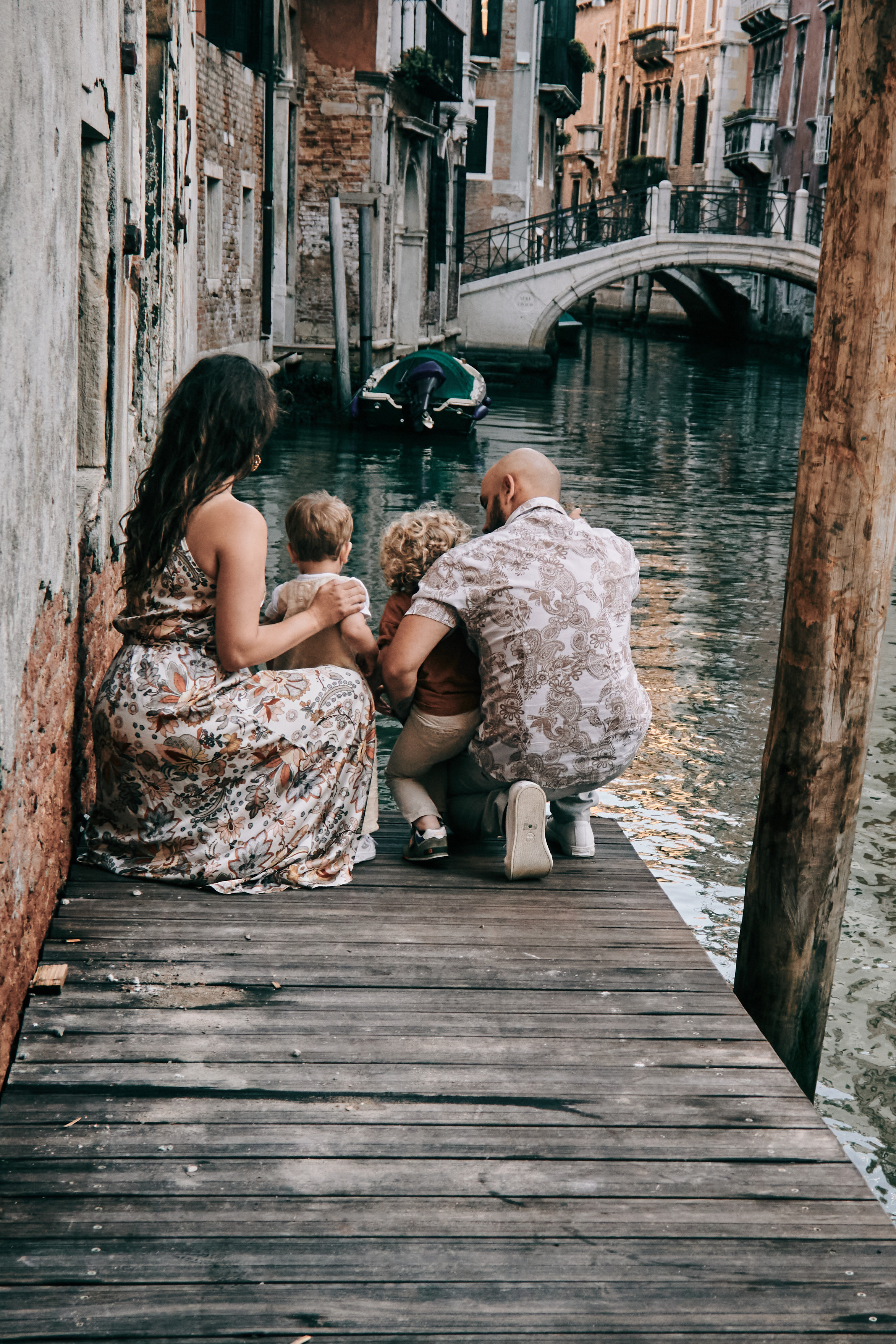 A family poses in front of a Venetian bridge, capturing their memorable vacation in Venice.