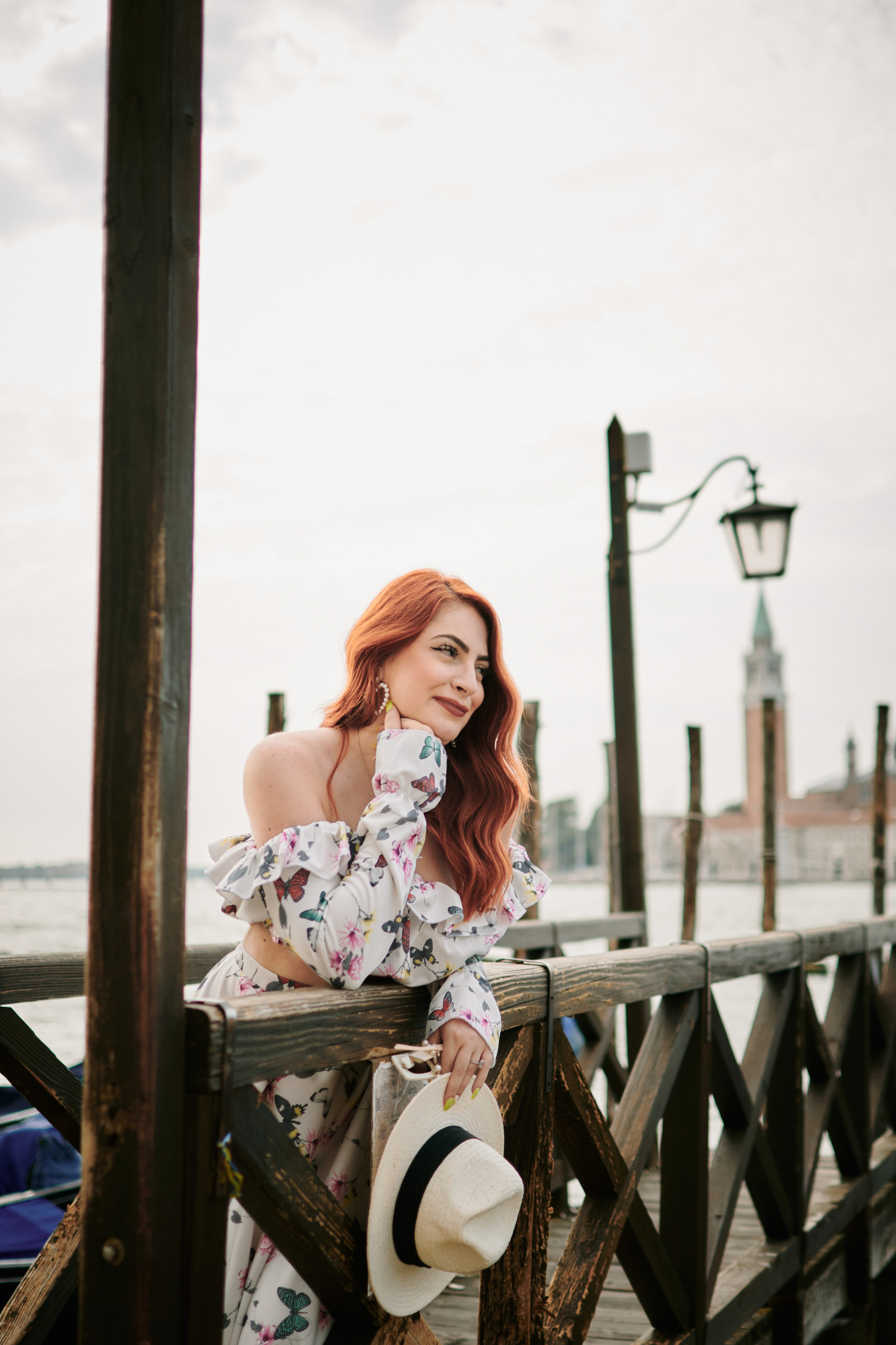 A radiant young woman  stands amidst the picturesque Colonna area of Venice. The soft light of the sun filters through the narrow alleyways, casting a warm glow on her face. The calm waters of the canal reflect the colorful buildings and arch bridges, alluding to the timeless beauty and serenity of the city. The woman's peaceful expression captures the joy and anticipation of impending motherhood, a moment frozen in time amidst the romantic backdrop of Venice.