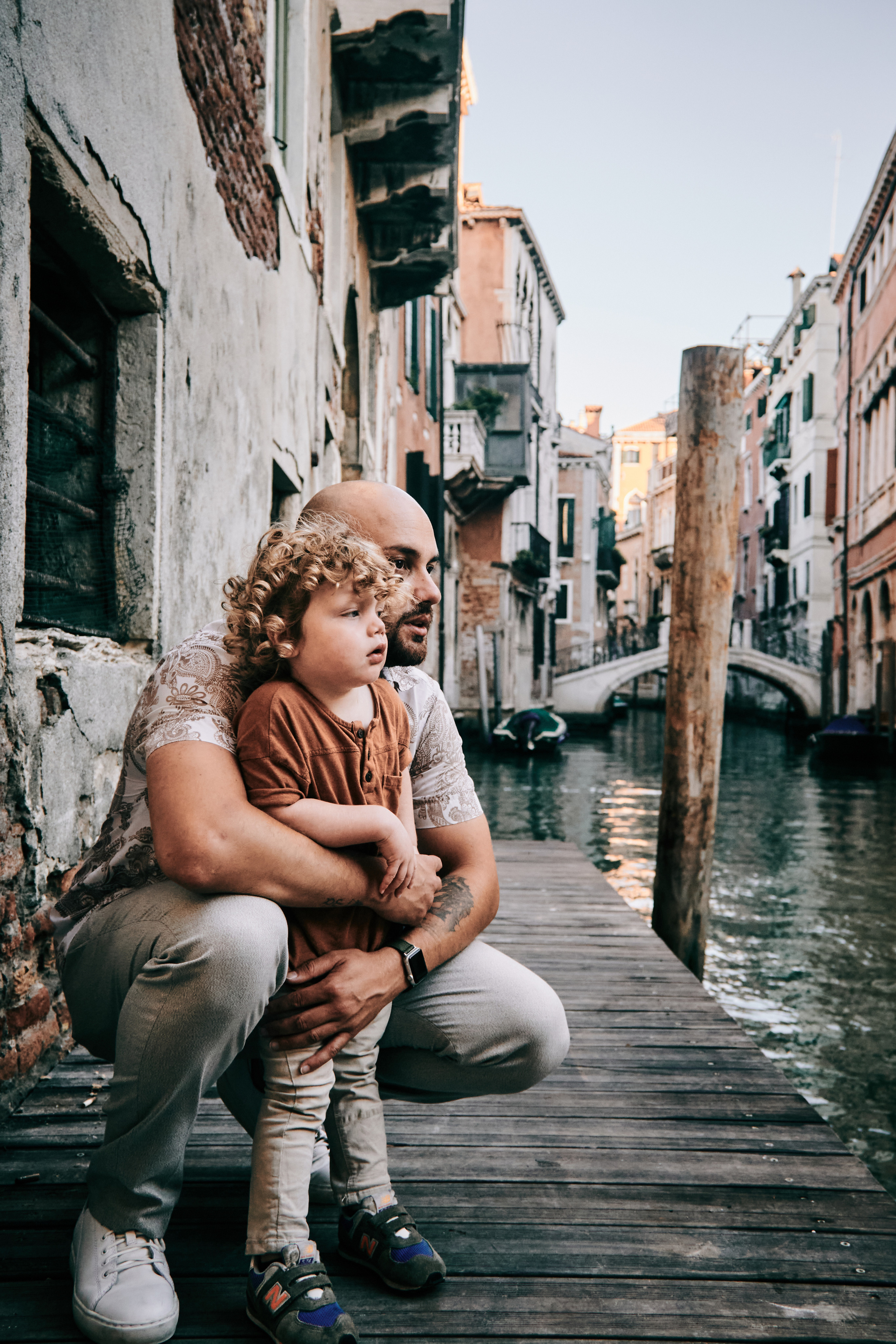 A family poses in front of a Venetian bridge, capturing their memorable vacation in Venice.