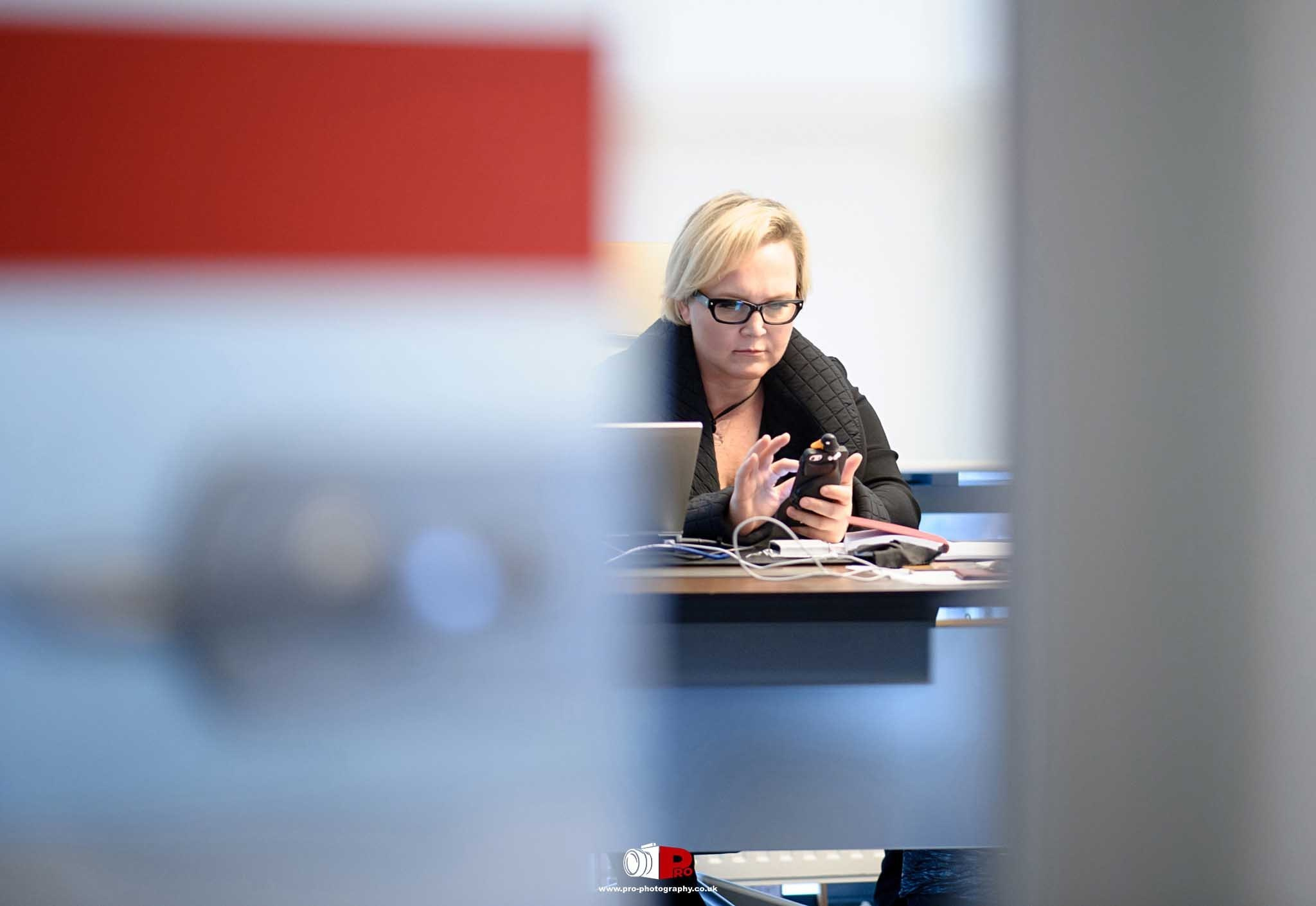 A professional blonde woman was engrossed in her smartphone while working in an office.